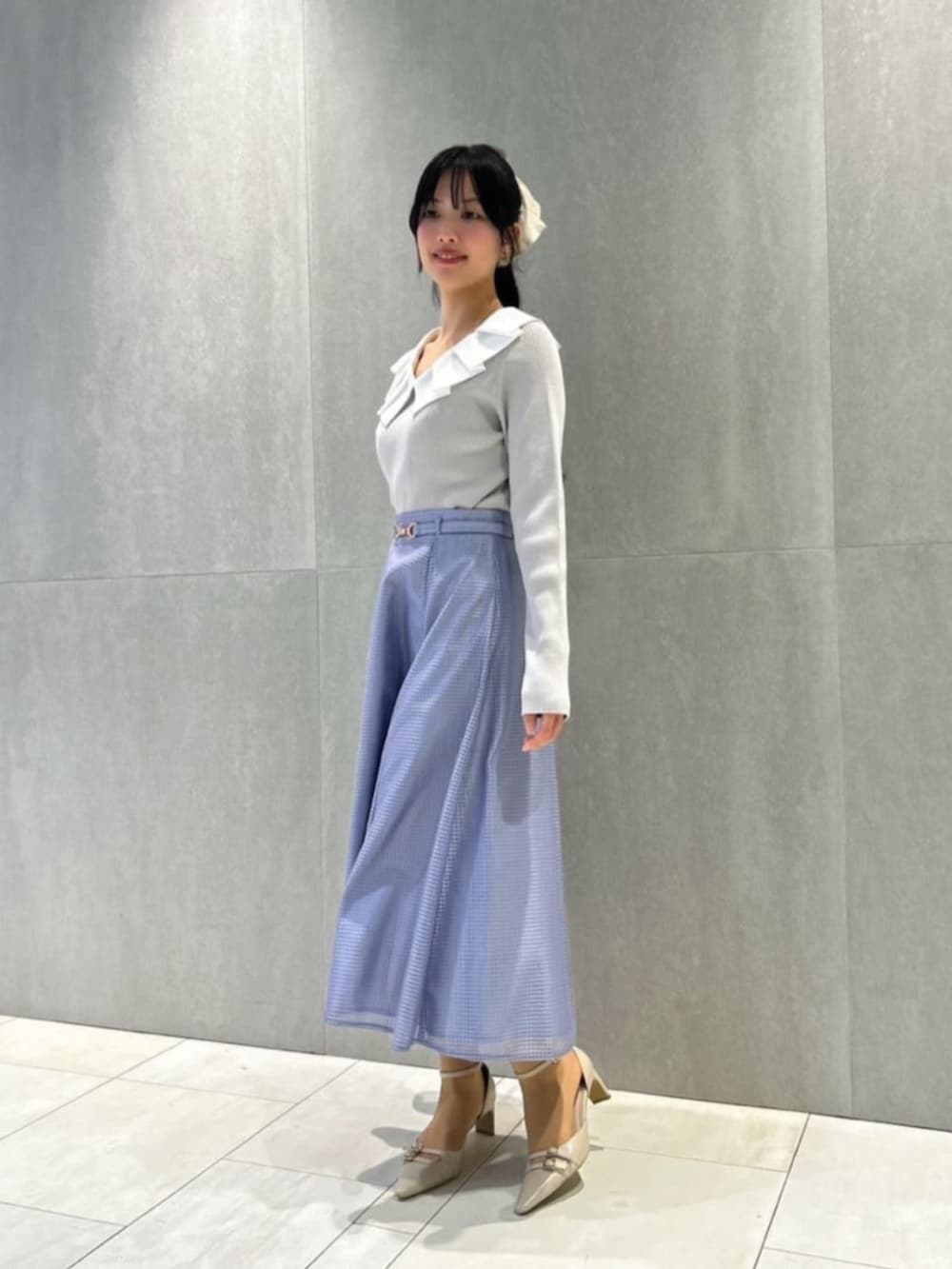 ベージュ系のパンプス、グレー系のニット/セーター、ブルー系のスカートを着用したレディースの春コーディネートの2枚目の写真