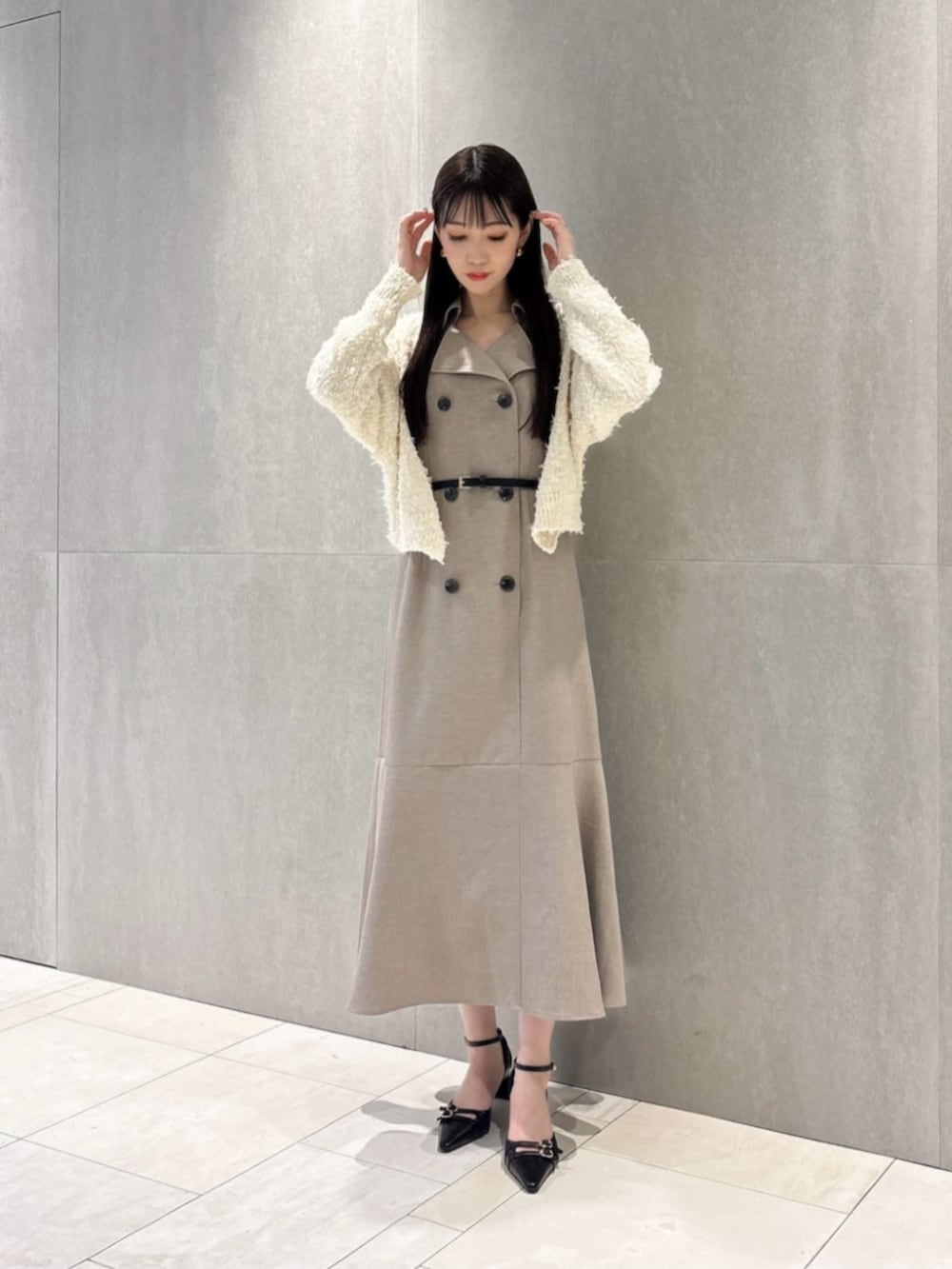 ブラック系のパンプス、ホワイト系のカーディガン/ボレロ、ベージュ系のワンピースを着用したレディースの春コーディネートの2枚目の写真