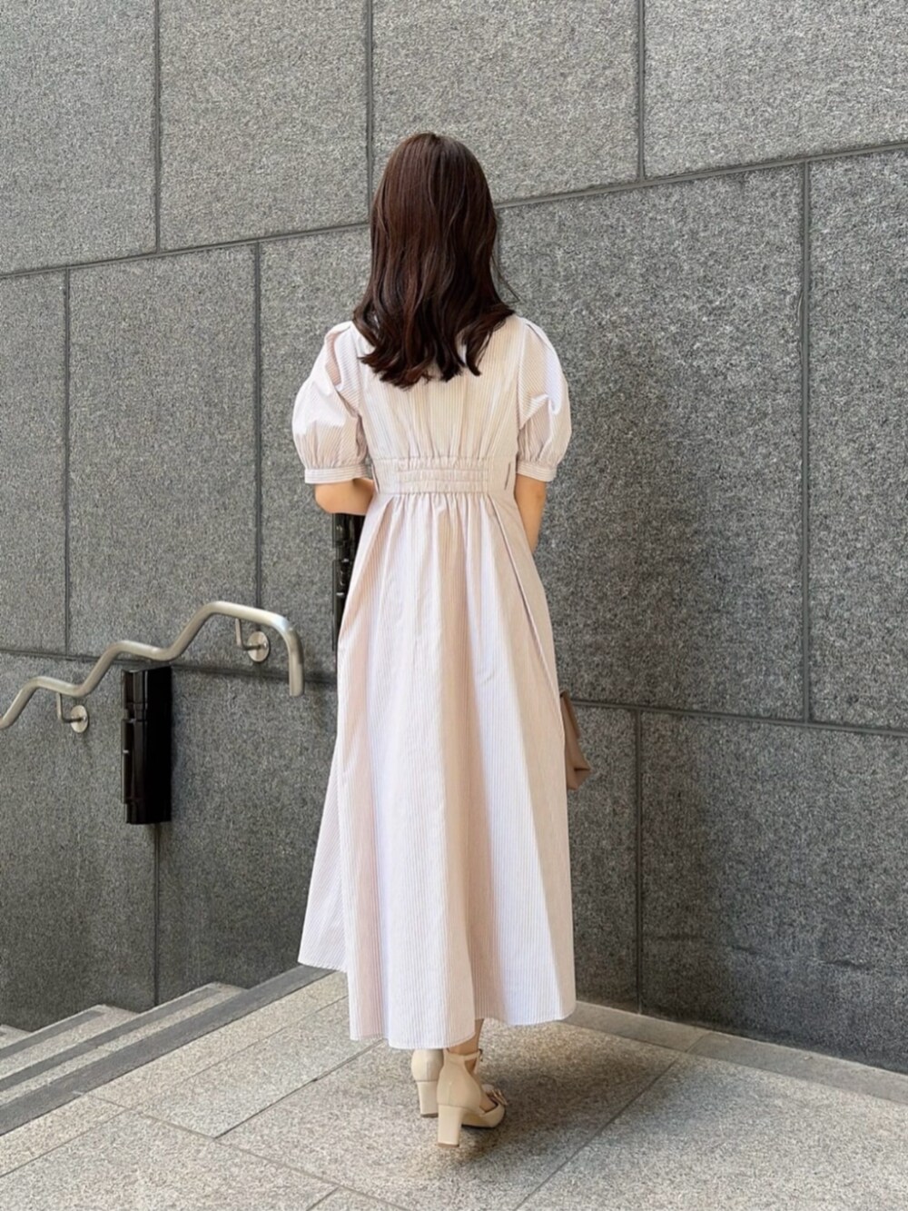 ベージュ系のパンプス、ベージュ系のワンピース、ブラウン系のトートバッグを着用したレディースの春コーディネートの4枚目の写真