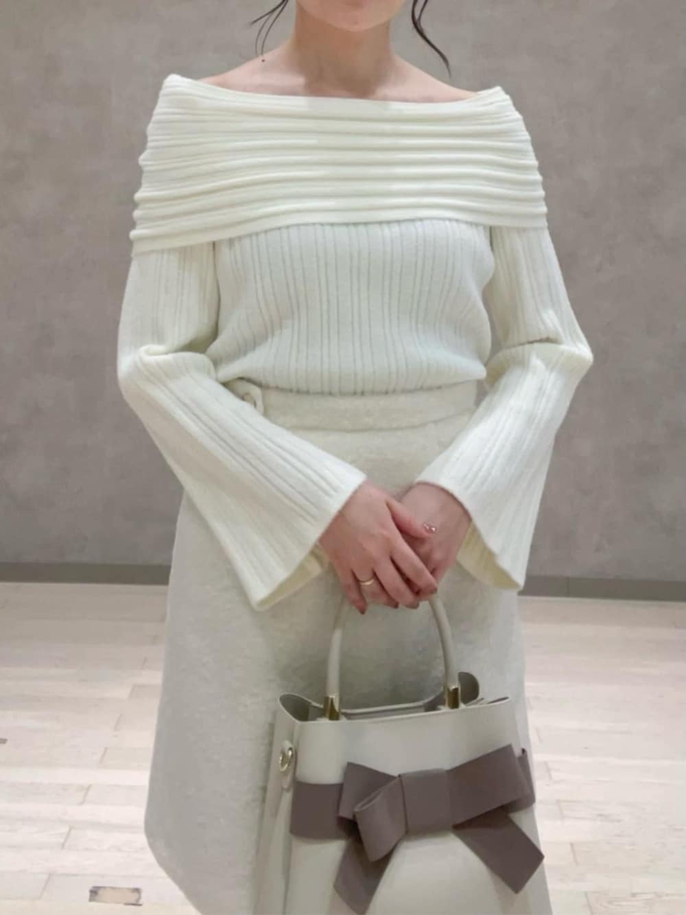 ベージュ系のショルダーバッグ、ホワイト系のスカート、ブラウン系のブーツを着用したレディースの冬コーディネートの3枚目の写真