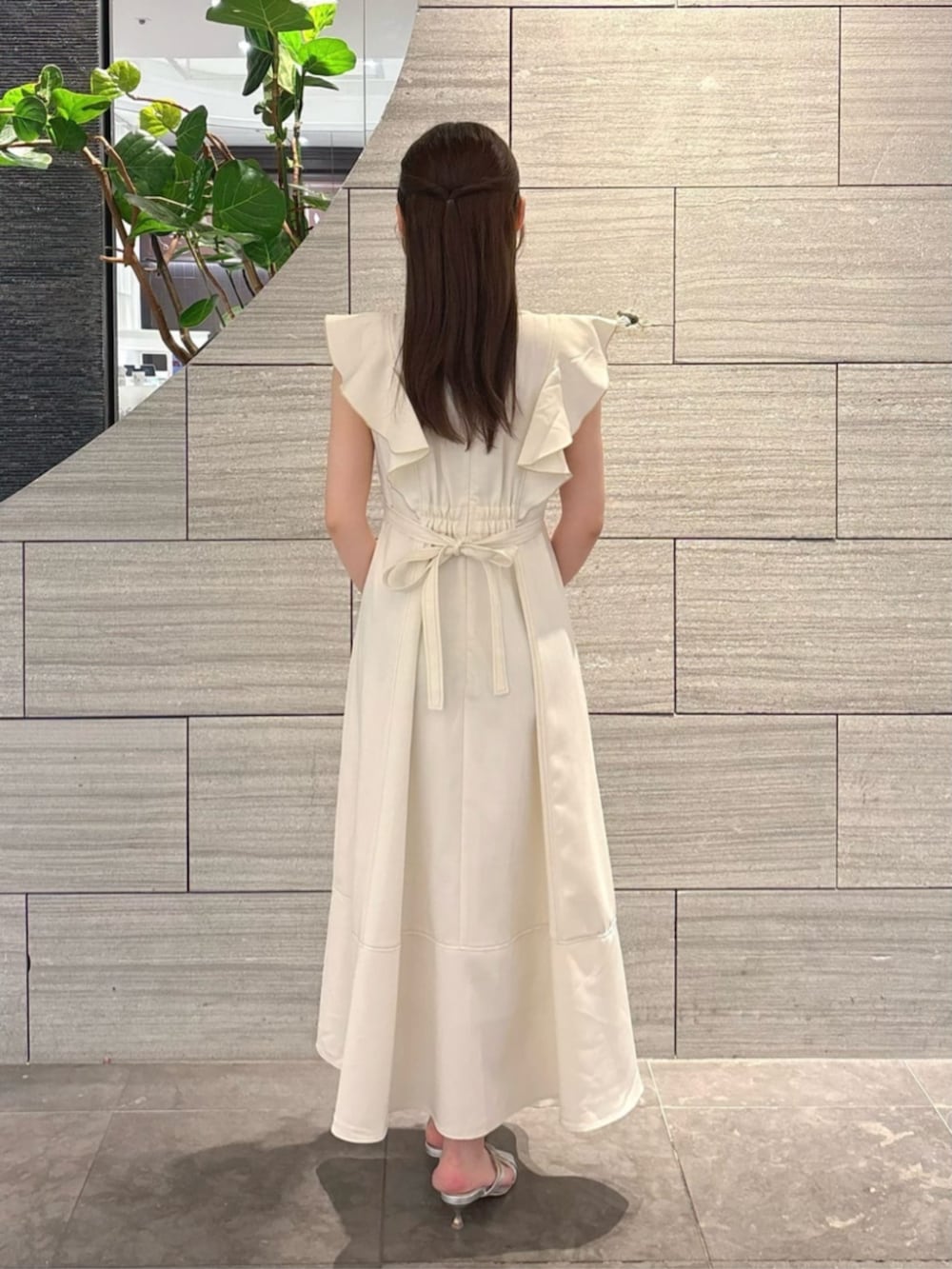 シルバー系のパンプス、グレー系のショルダーバッグ、ベージュ系のワンピースを着用したレディースの夏コーディネートの3枚目の写真