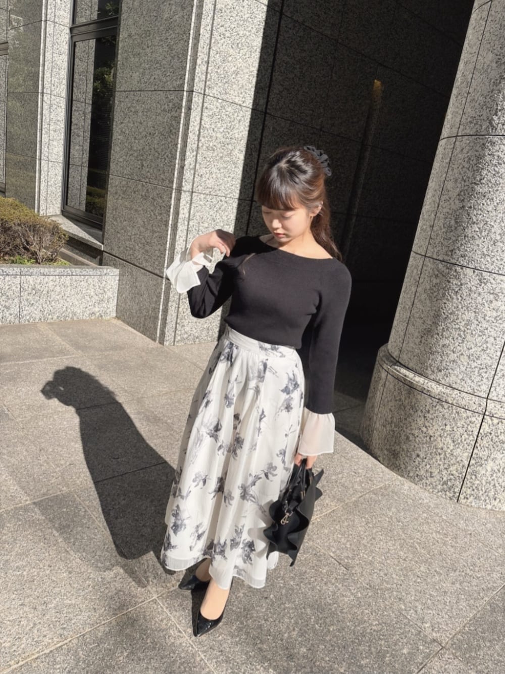 グレー系のスカート、ブラック系のニット/セーターを着用したレディースの冬コーディネートの2枚目の写真