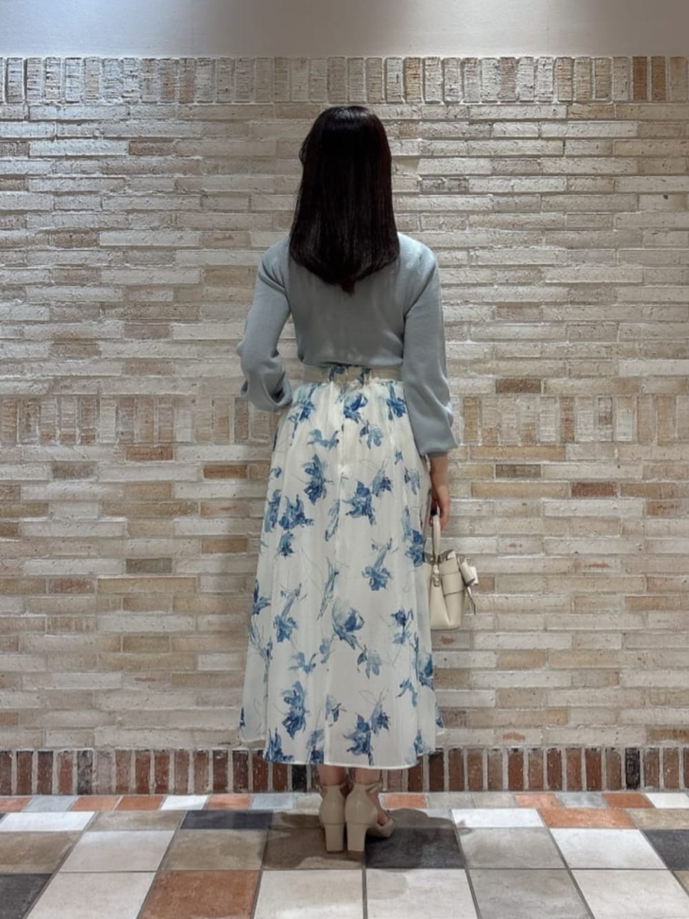 ホワイト系のショルダーバッグ、ベージュ系のパンプス、グリーン系のニット/セーターを着用したレディースの冬コーディネートの3枚目の写真