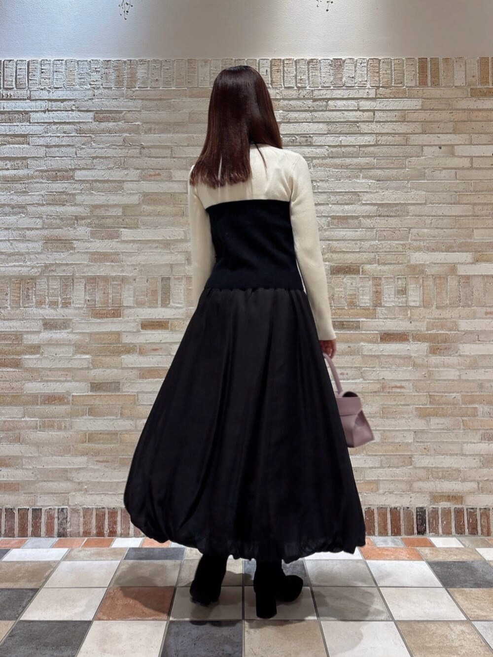 ブラック系のニット/セーター、ブラック系のスカート、パープル系のトートバッグを着用したレディースの秋コーディネートの2枚目の写真