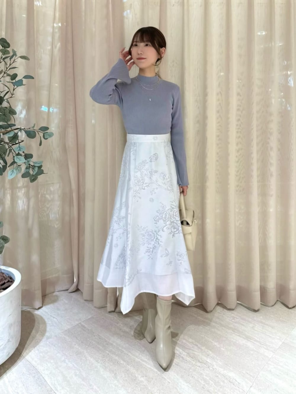 ホワイト系のトートバッグ、ブルー系のニット/セーター、ホワイト系のスカートを着用したレディースの冬コーディネートの2枚目の写真