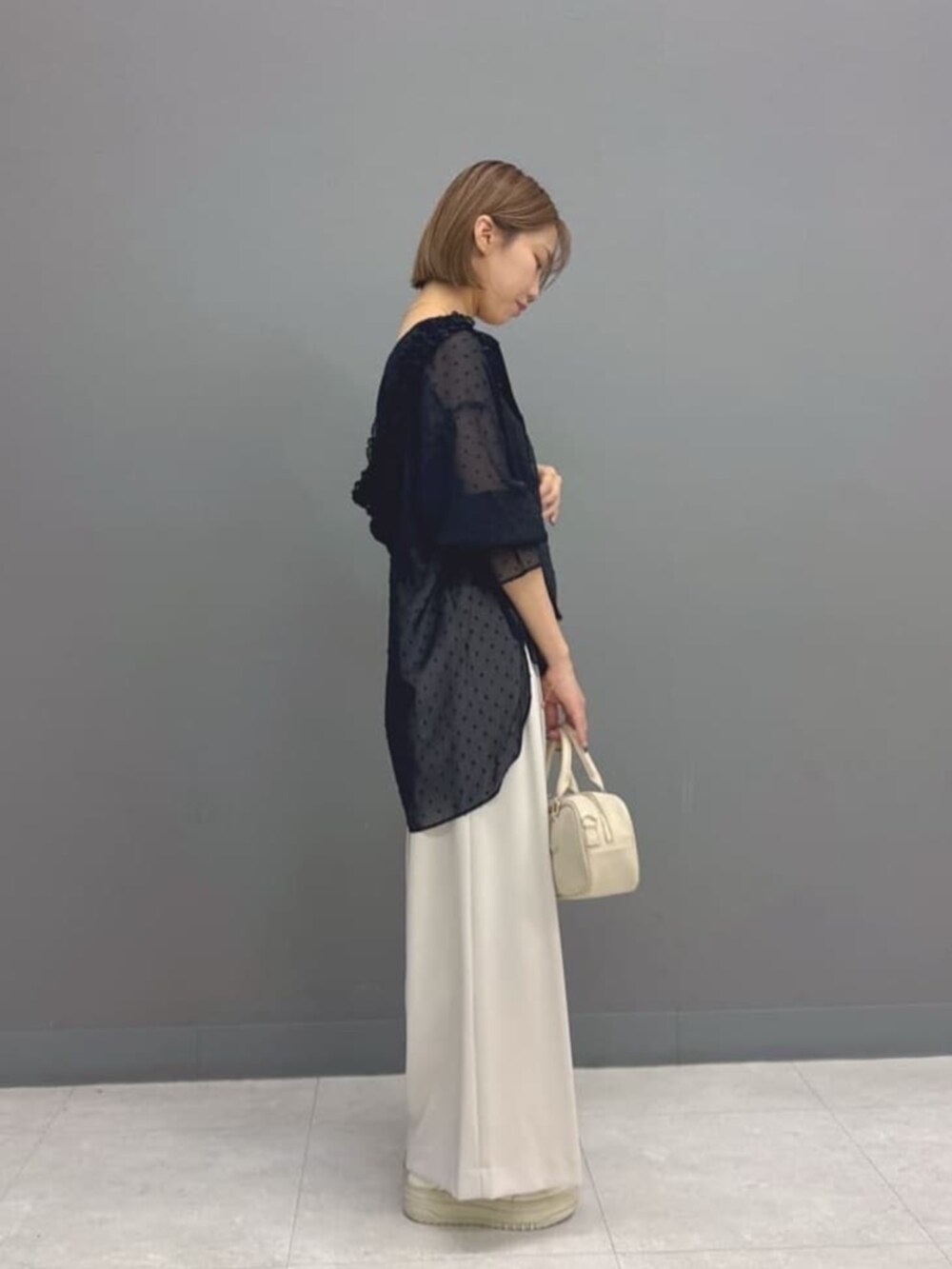 ブラック系のシャツ/ブラウス、グレー系のその他パンツ、ホワイト系のボストンバッグを着用したレディースの秋コーディネートの2枚目の写真