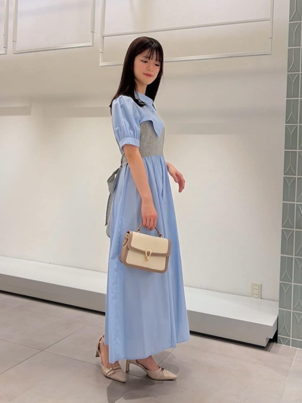 ベージュ系のパンプス、グレー系のショルダーバッグ、ブルー系のワンピースを着用したレディースの春コーディネートの2枚目の写真