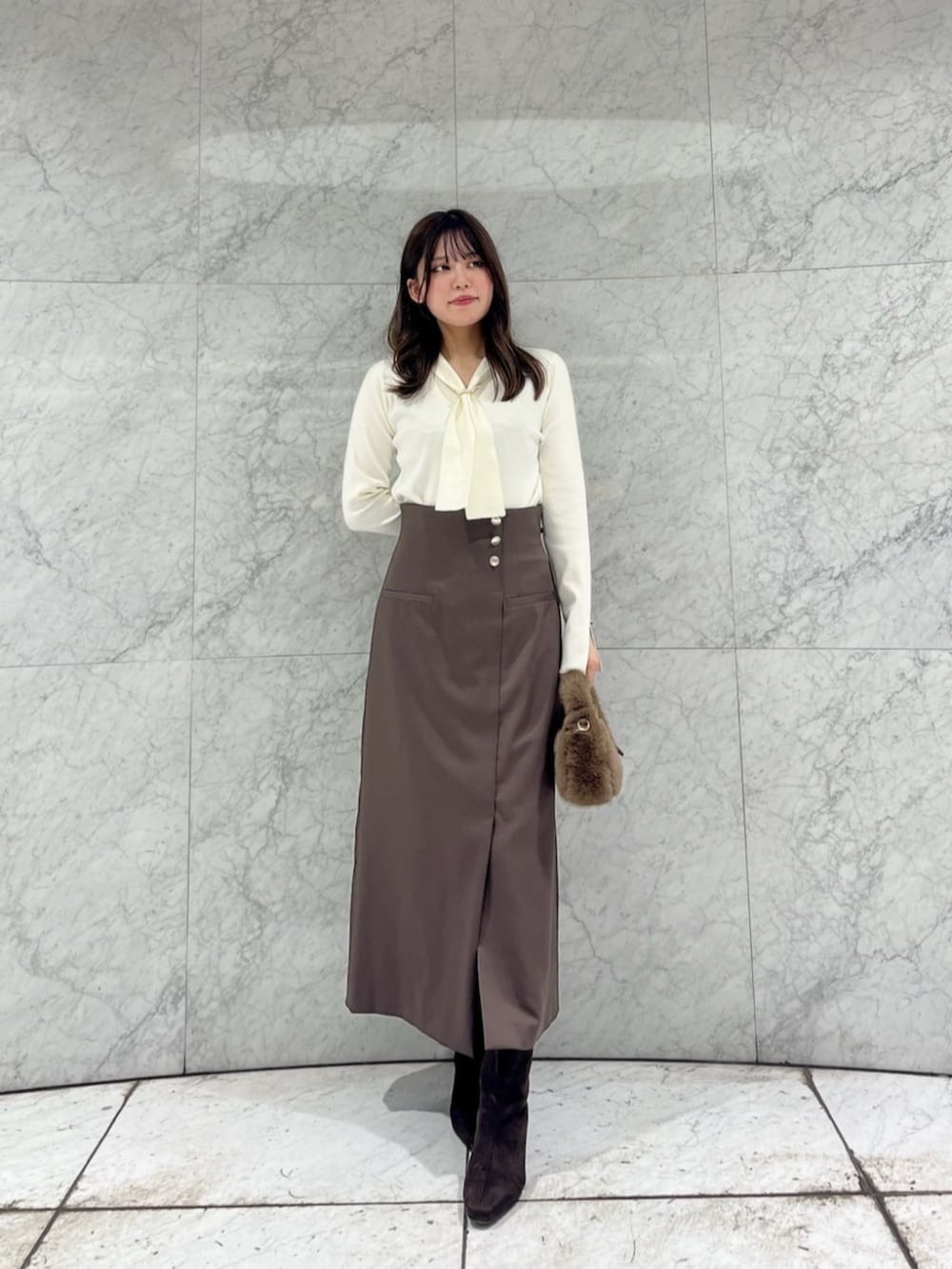 ホワイト系のニット/セーター、ベージュ系のノーカラーコート、ブラウン系のスカートを着用したレディースの秋コーディネートの3枚目の写真