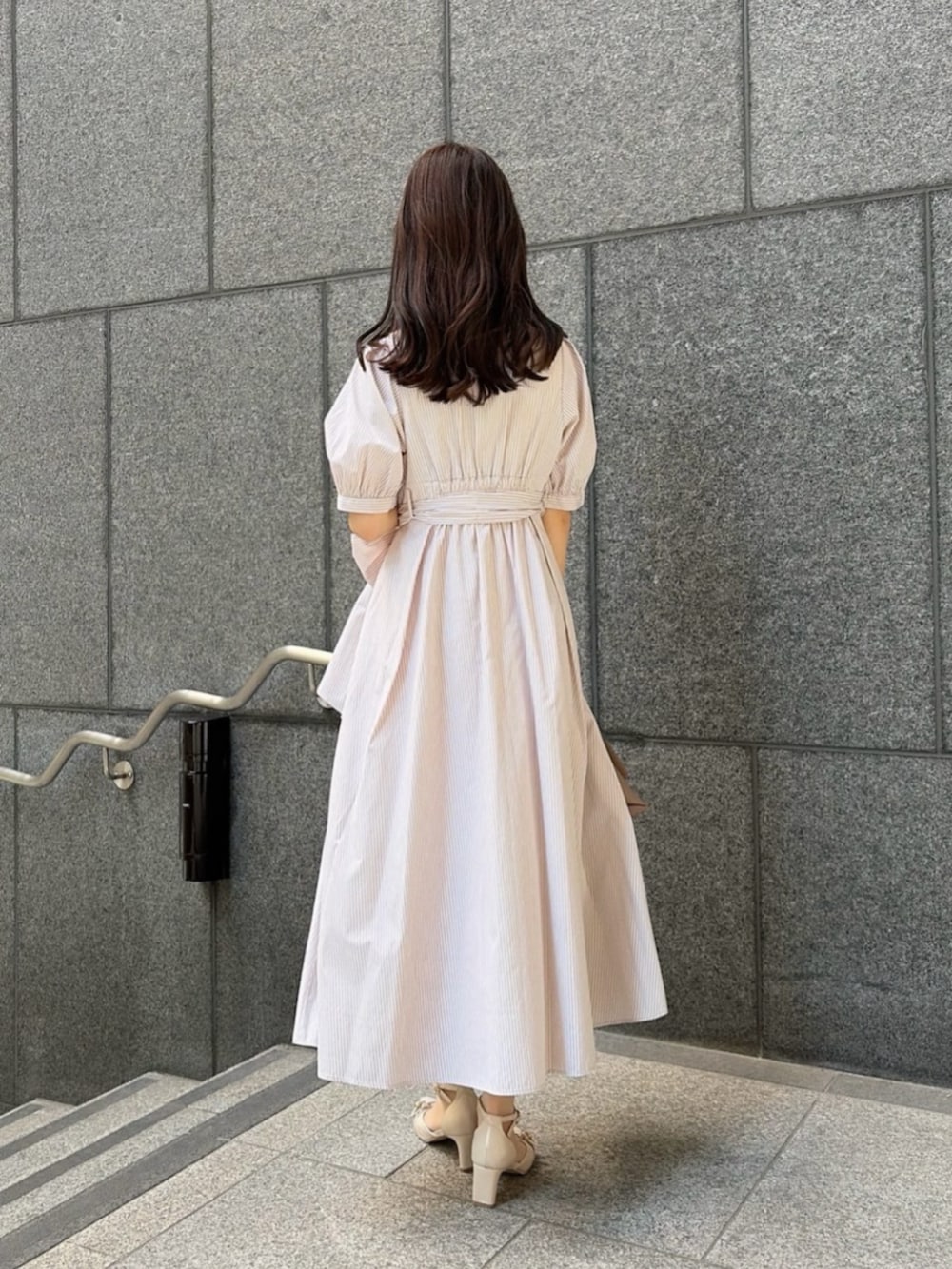 ベージュ系のパンプス、ベージュ系のワンピース、ブラウン系のトートバッグを着用したレディースの春コーディネートの5枚目の写真
