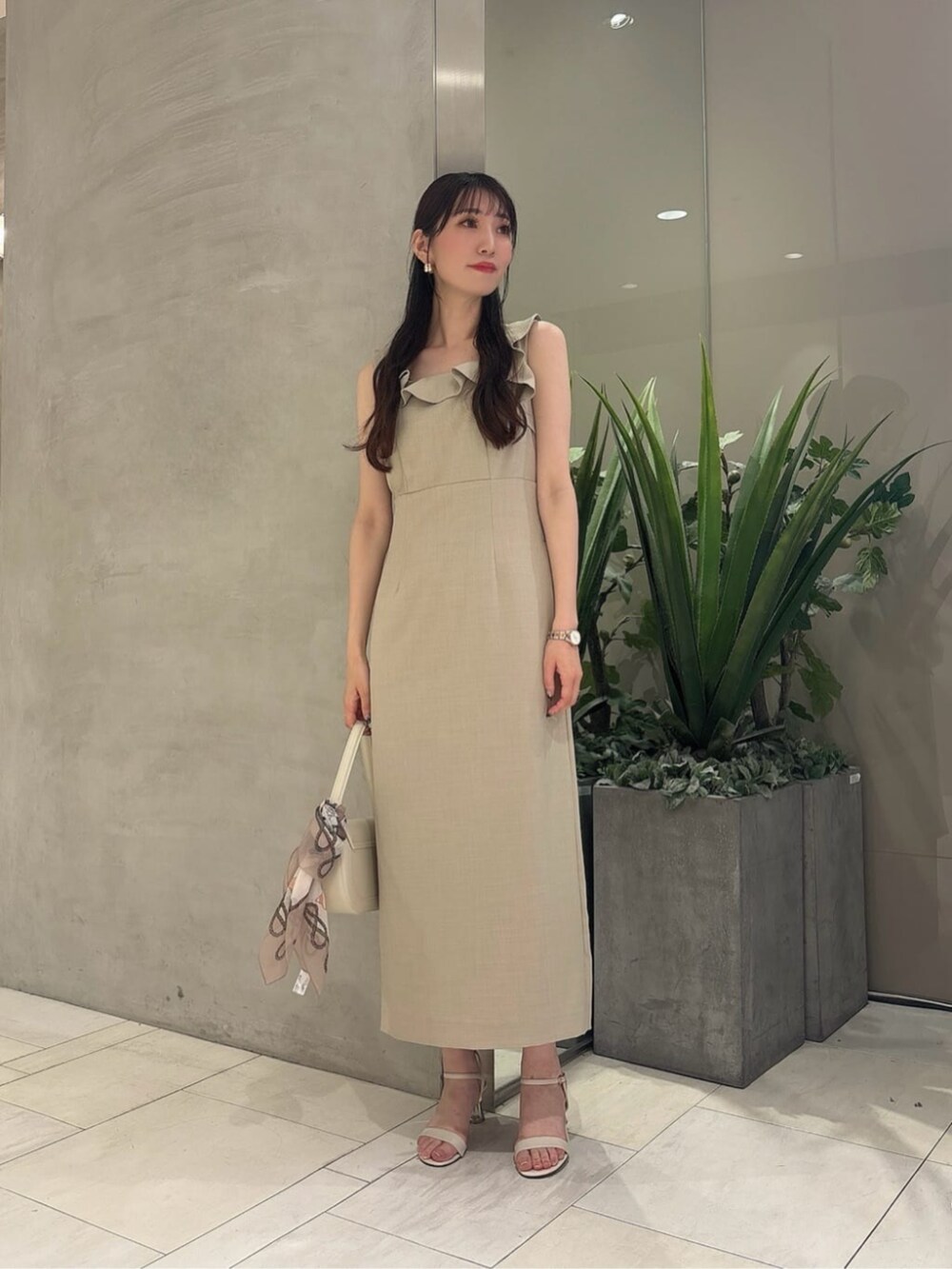 ホワイト系のショルダーバッグ、ベージュ系のワンピース、ベージュ系のストール/ショールを着用したレディースの夏コーディネートの2枚目の写真