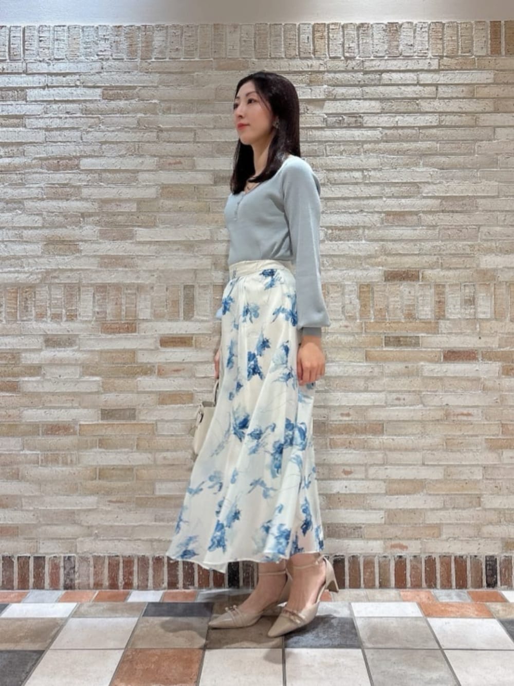 ホワイト系のショルダーバッグ、ベージュ系のパンプス、グリーン系のニット/セーターを着用したレディースの冬コーディネートの2枚目の写真