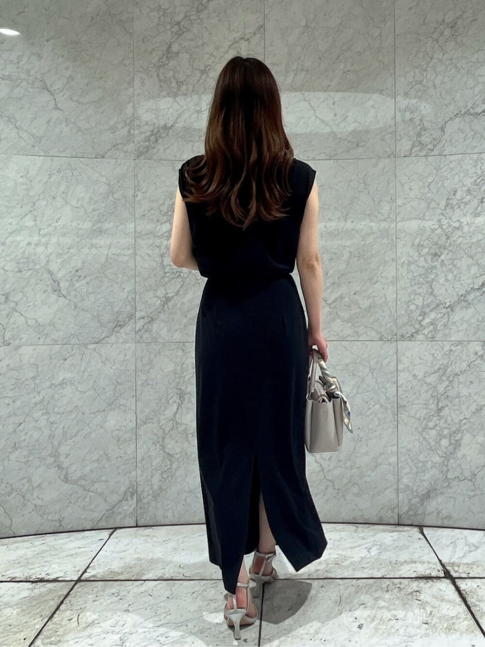 シルバー系のパンプス、ブラック系のワンピース、グレー系のトートバッグを着用したレディースの夏コーディネートの3枚目の写真