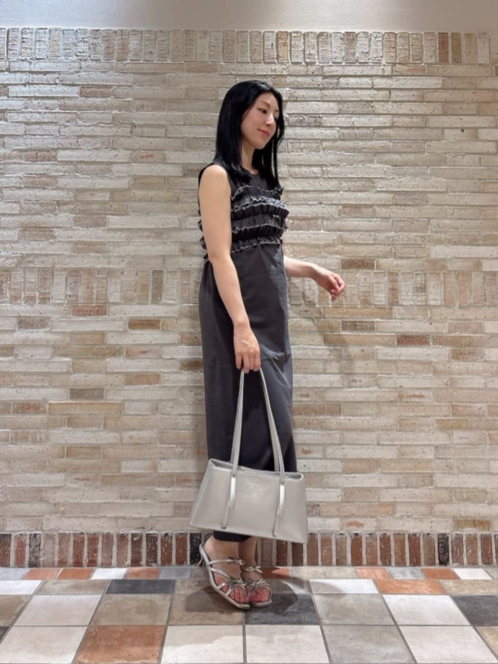 シルバー系のパンプス、シルバー系のショルダーバッグ、グレー系のワンピースを着用したレディースの夏コーディネートの2枚目の写真