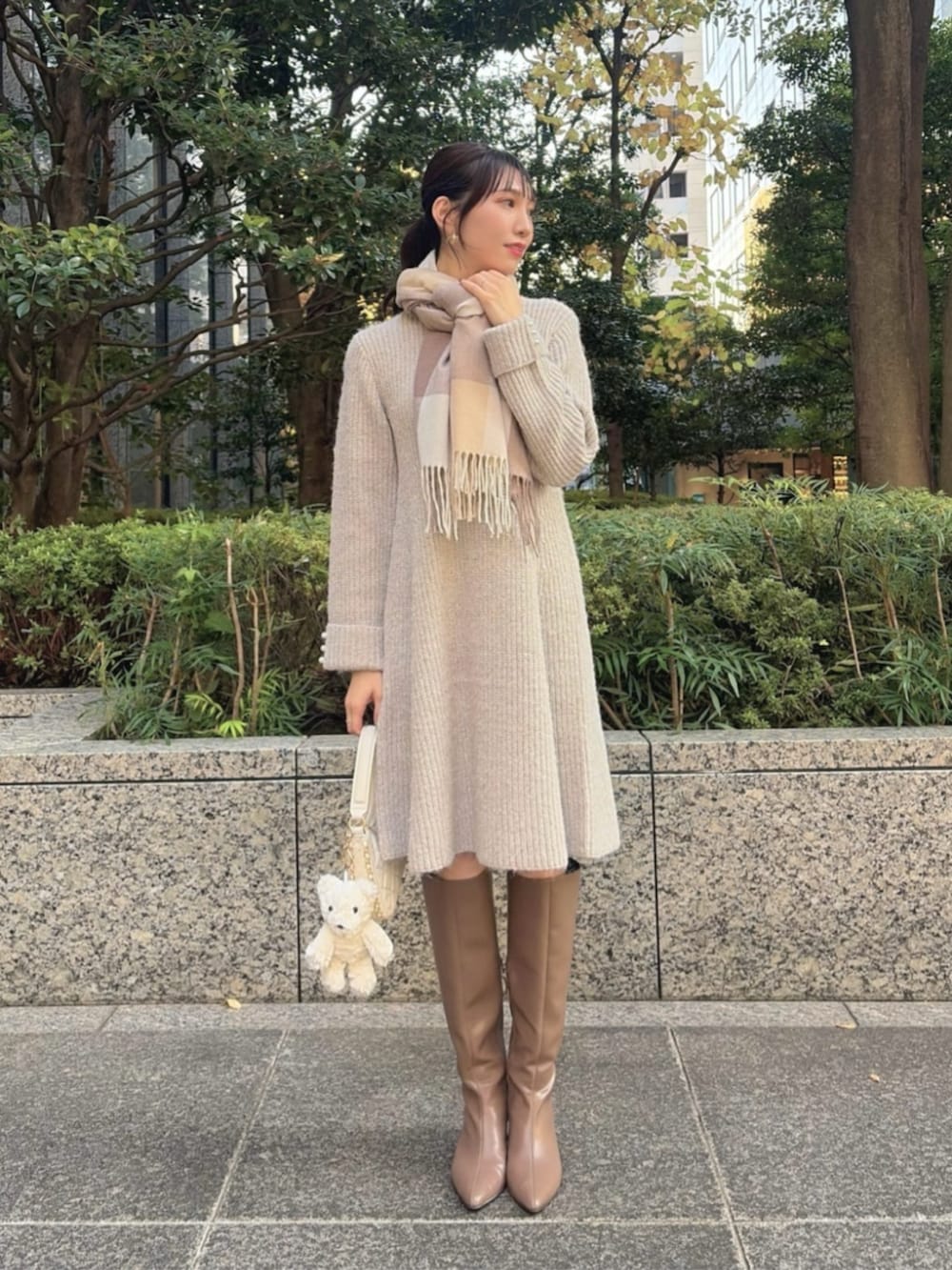 ブラウン系のブーツ、ホワイト系のショルダーバッグ、ベージュ系のワンピースを着用したレディースの冬コーディネートの2枚目の写真