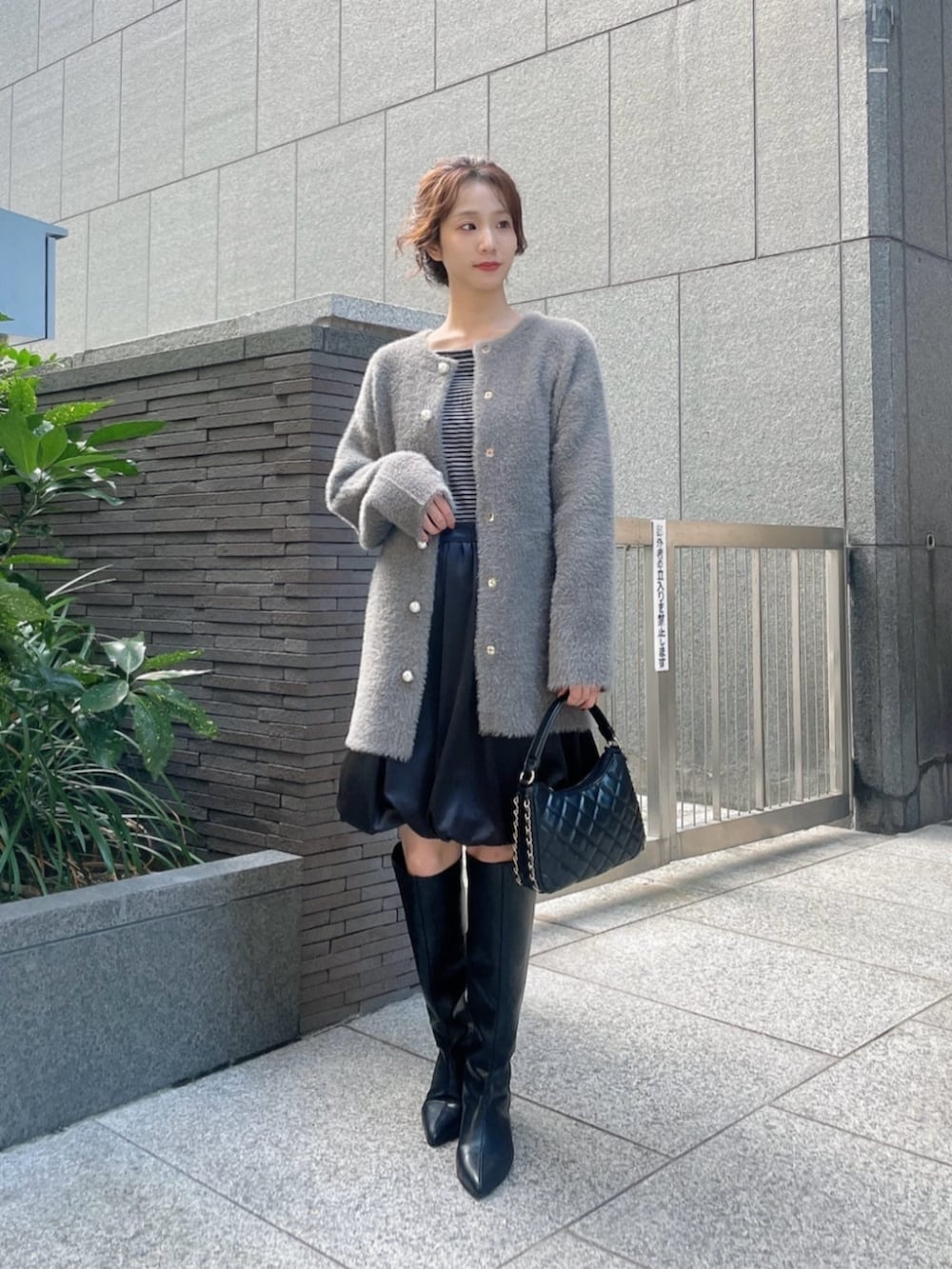 グレー系のテーラードジャケット、ブラック系のスカート、ブラック系のブーツを着用したレディースの秋コーディネートの3枚目の写真