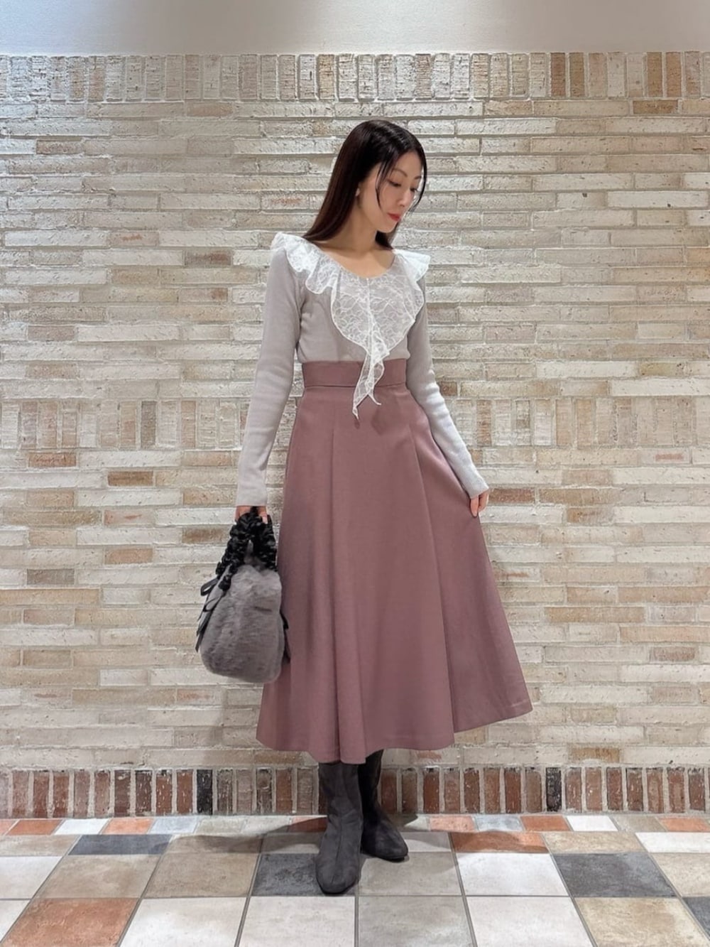 グレー系のトートバッグ、グレー系のニット/セーター、ピンク系のスカートを着用したレディースの秋コーディネートの2枚目の写真