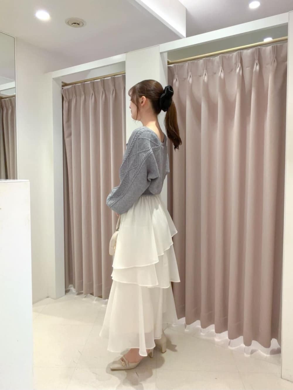 ベージュ系のパンプス、ホワイト系のボストンバッグ、ホワイト系のスカートを着用したレディースの秋コーディネートの2枚目の写真