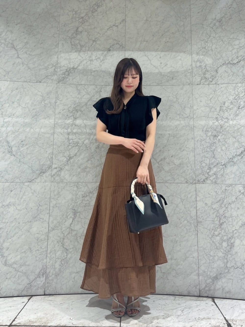 シルバー系のパンプス、ブラック系のニット/セーター、ブラウン系のスカートを着用したレディースの夏コーディネートの3枚目の写真