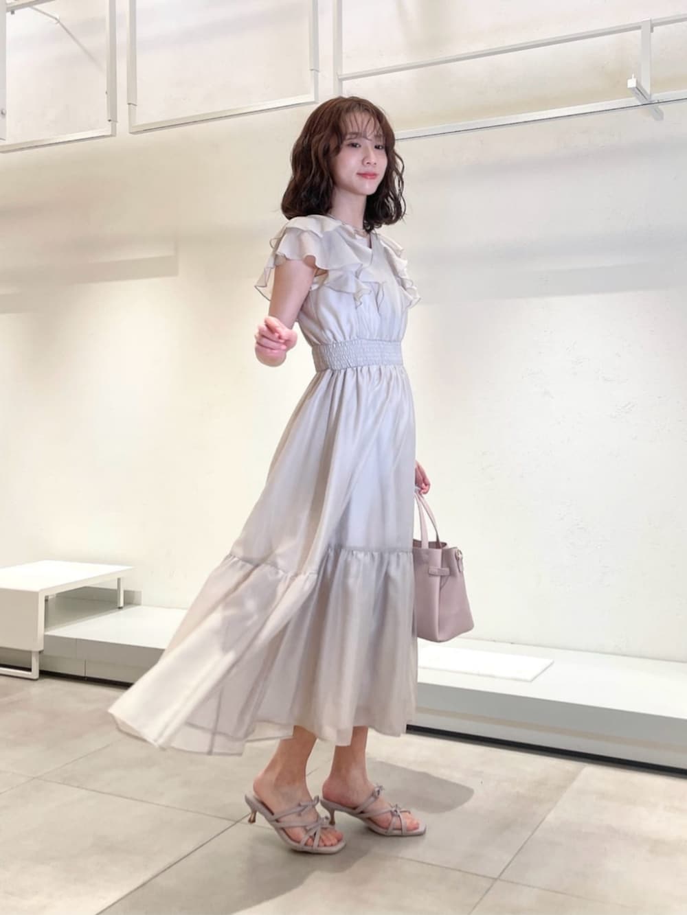 グレー系のワンピース、ピンク系のトートバッグ、パープル系のパンプスを着用したレディースの春コーディネートの2枚目の写真