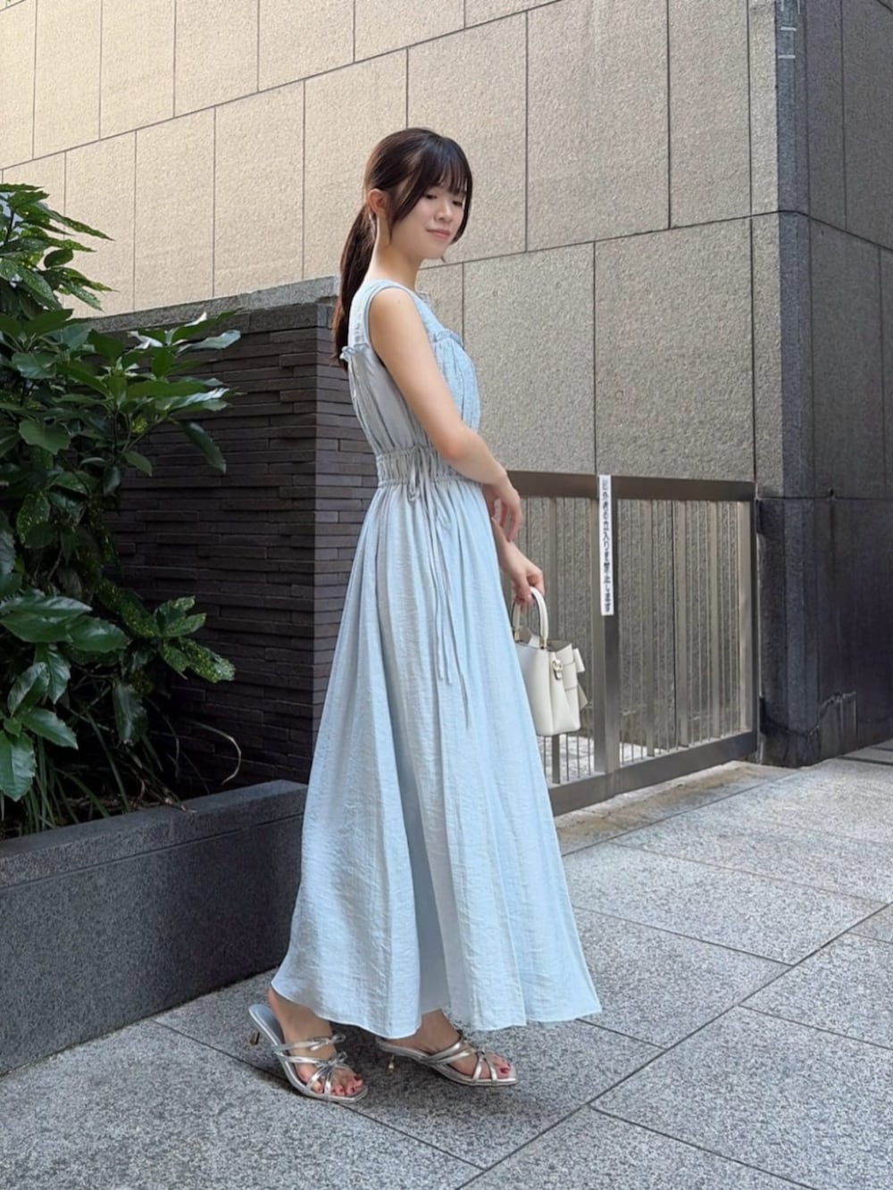シルバー系のパンプス、ブルー系のワンピース、ホワイト系のショルダーバッグを着用したレディースの夏コーディネートの2枚目の写真