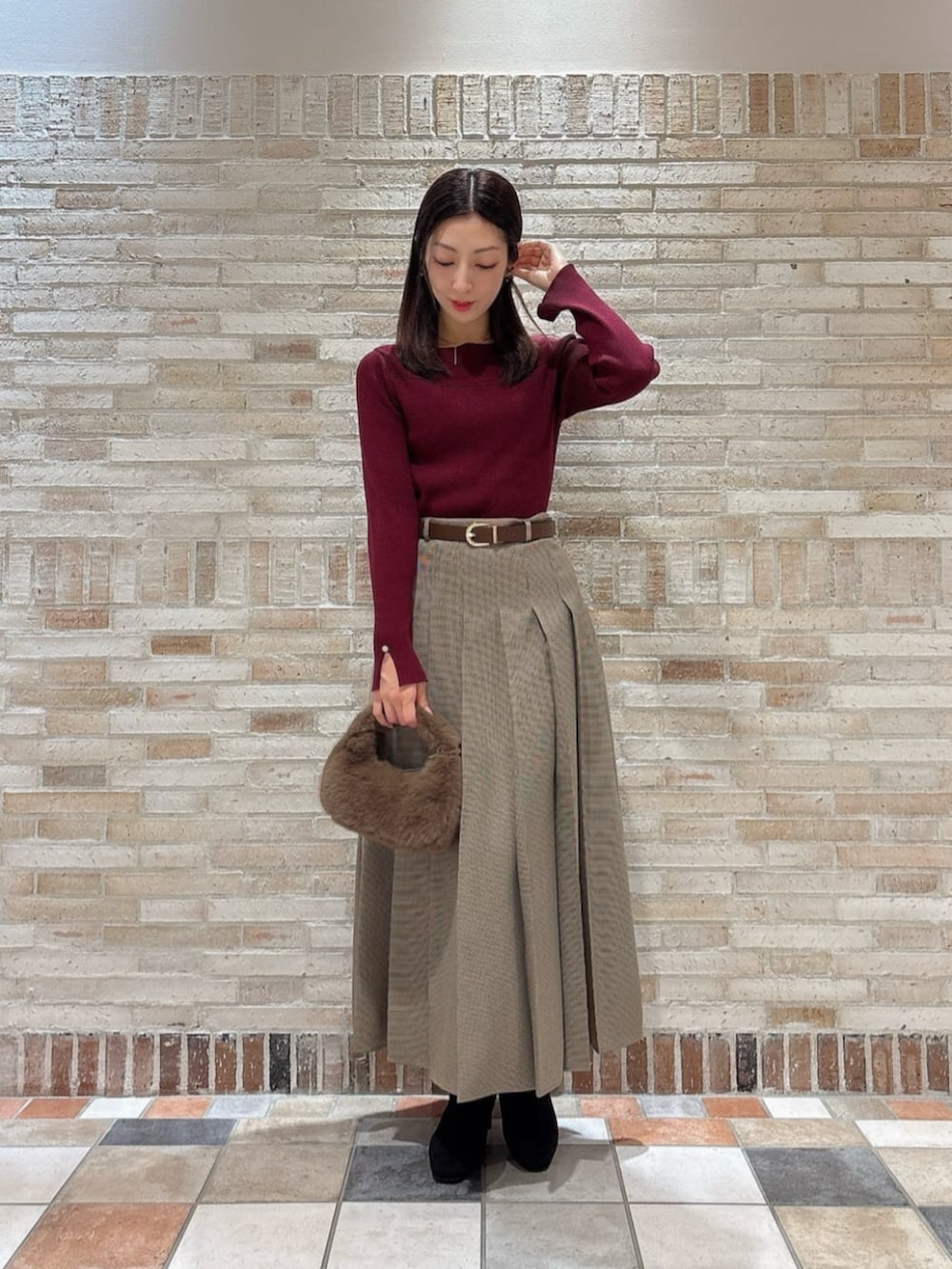 ブラウン系のスカート、レッド系のニット/セーター、ブラウン系のハンドバッグを着用したレディースの秋コーディネートの3枚目の写真