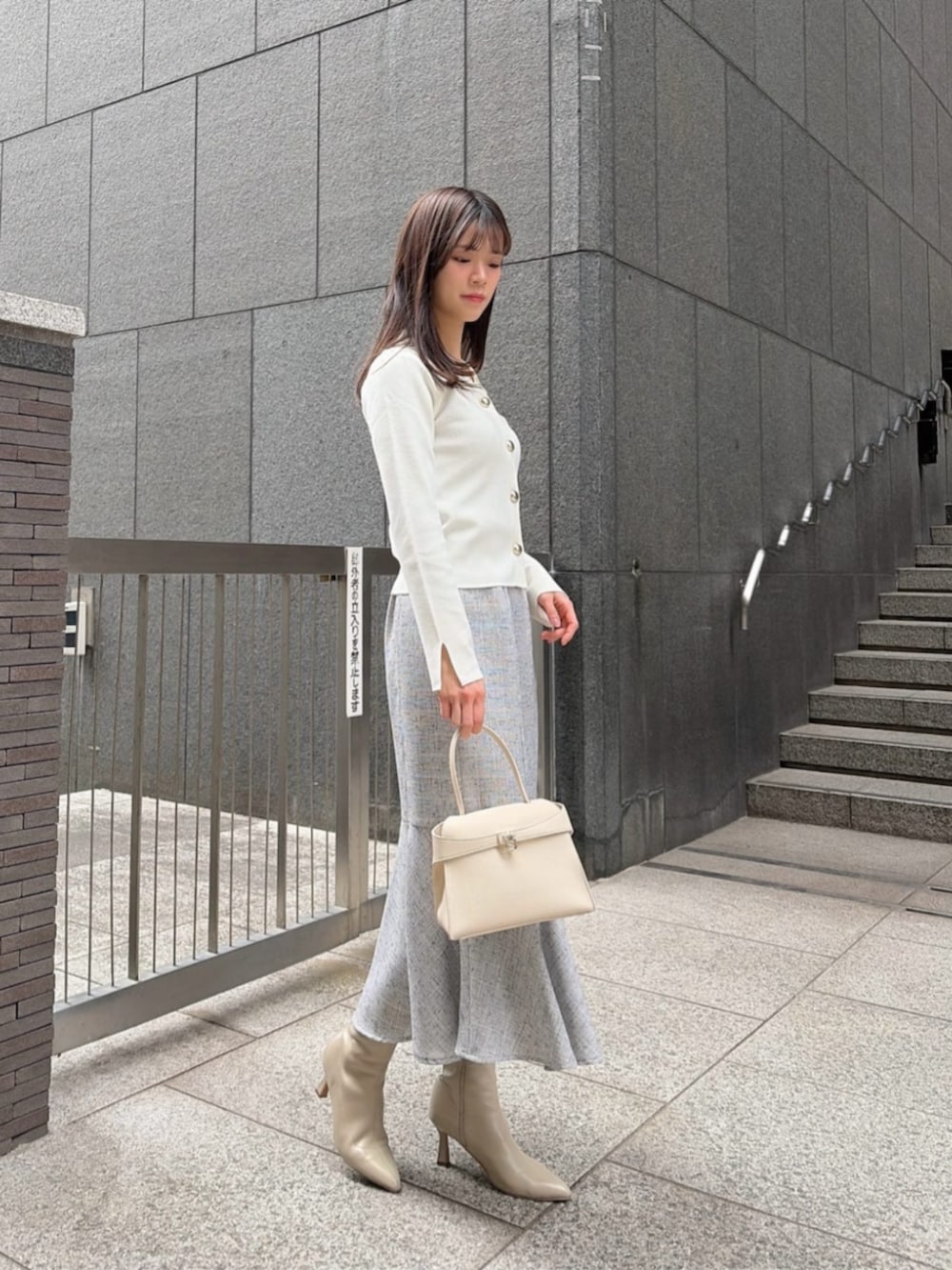 ホワイト系のトートバッグ、ホワイト系のニット/セーター、ブラック系のスカートを着用したレディースの冬コーディネートの2枚目の写真