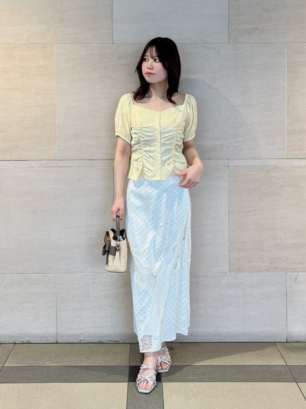 シルバー系のパンプス、ホワイト系のスカート、イエロー系のシャツ/ブラウスを着用したレディースの夏コーディネートの2枚目の写真