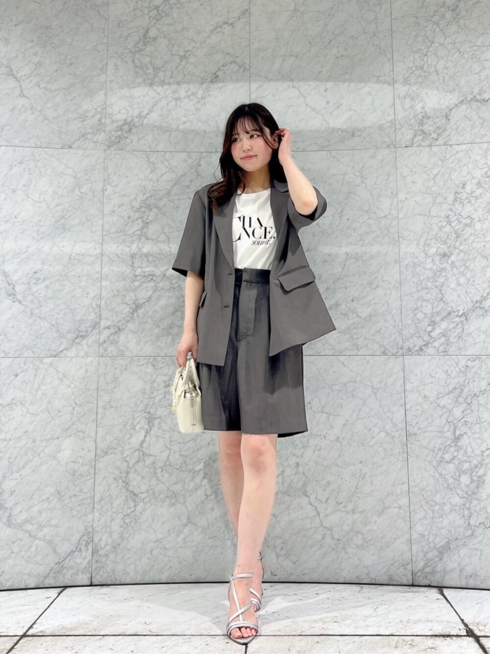ホワイト系のTシャツ/カットソー、シルバー系のパンプス、グレー系のテーラードジャケットを着用したレディースの春コーディネートの2枚目の写真