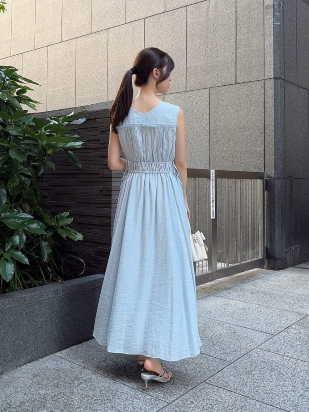 シルバー系のパンプス、ブルー系のワンピース、ホワイト系のショルダーバッグを着用したレディースの夏コーディネートの3枚目の写真