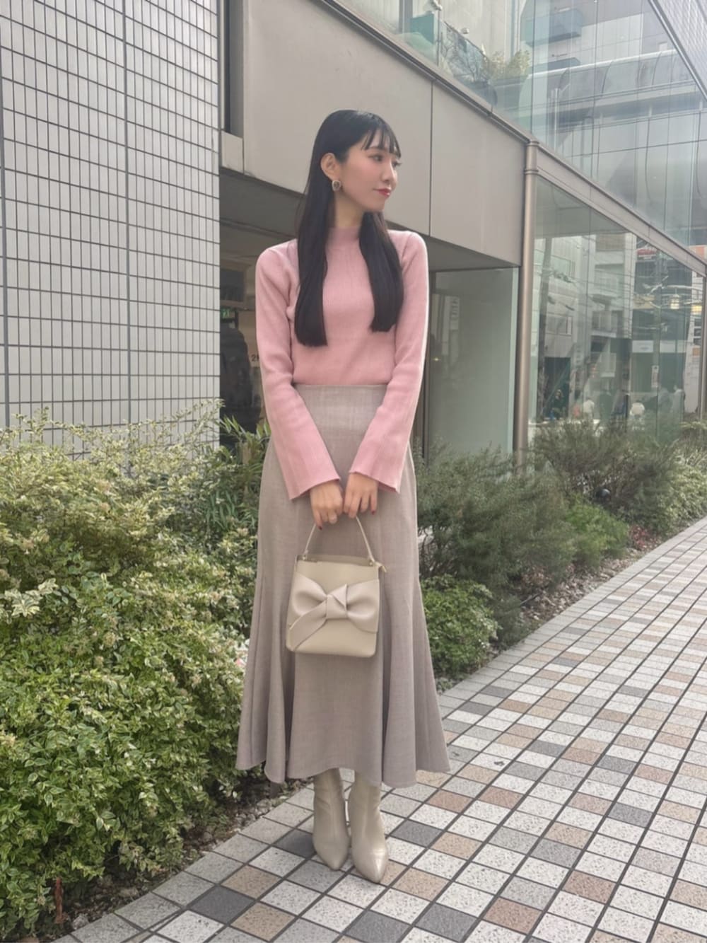 ピンク系のニット/セーター、ブラウン系のスカート、ベージュ系のショルダーバッグを着用したレディースの冬コーディネートの3枚目の写真