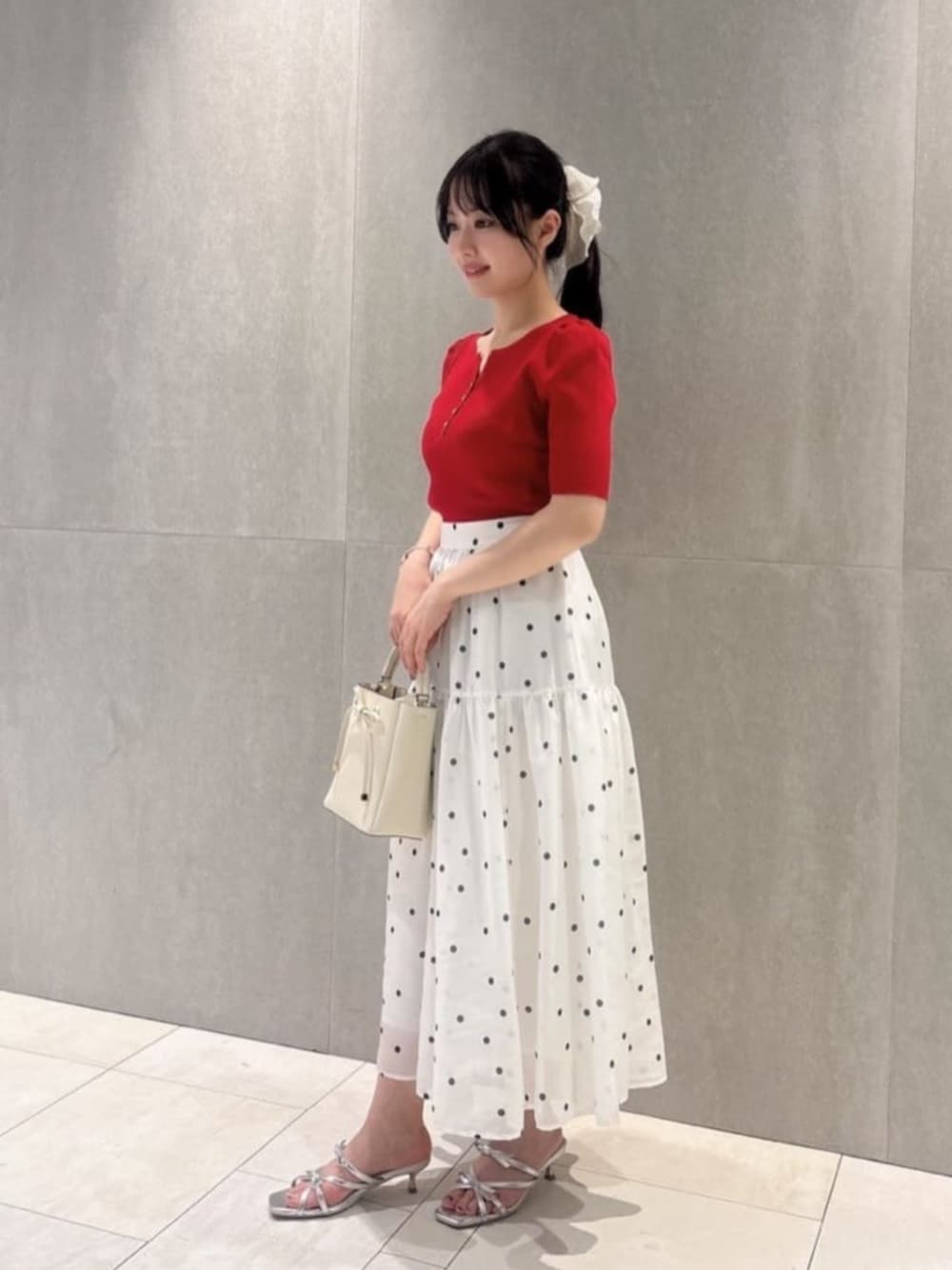ホワイト系のショルダーバッグ、シルバー系のパンプス、レッド系のニット/セーターを着用したレディースの春コーディネートの3枚目の写真
