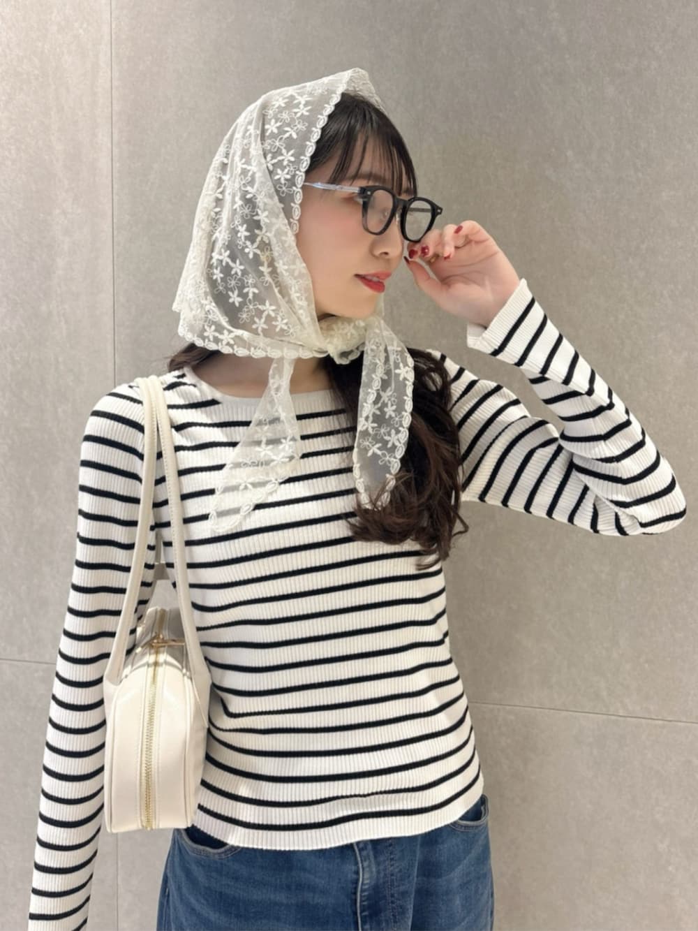 ブルー系のデニムパンツ、ホワイト系のショルダーバッグ、ホワイト系のニット/セーターを着用したレディースの春コーディネートの3枚目の写真