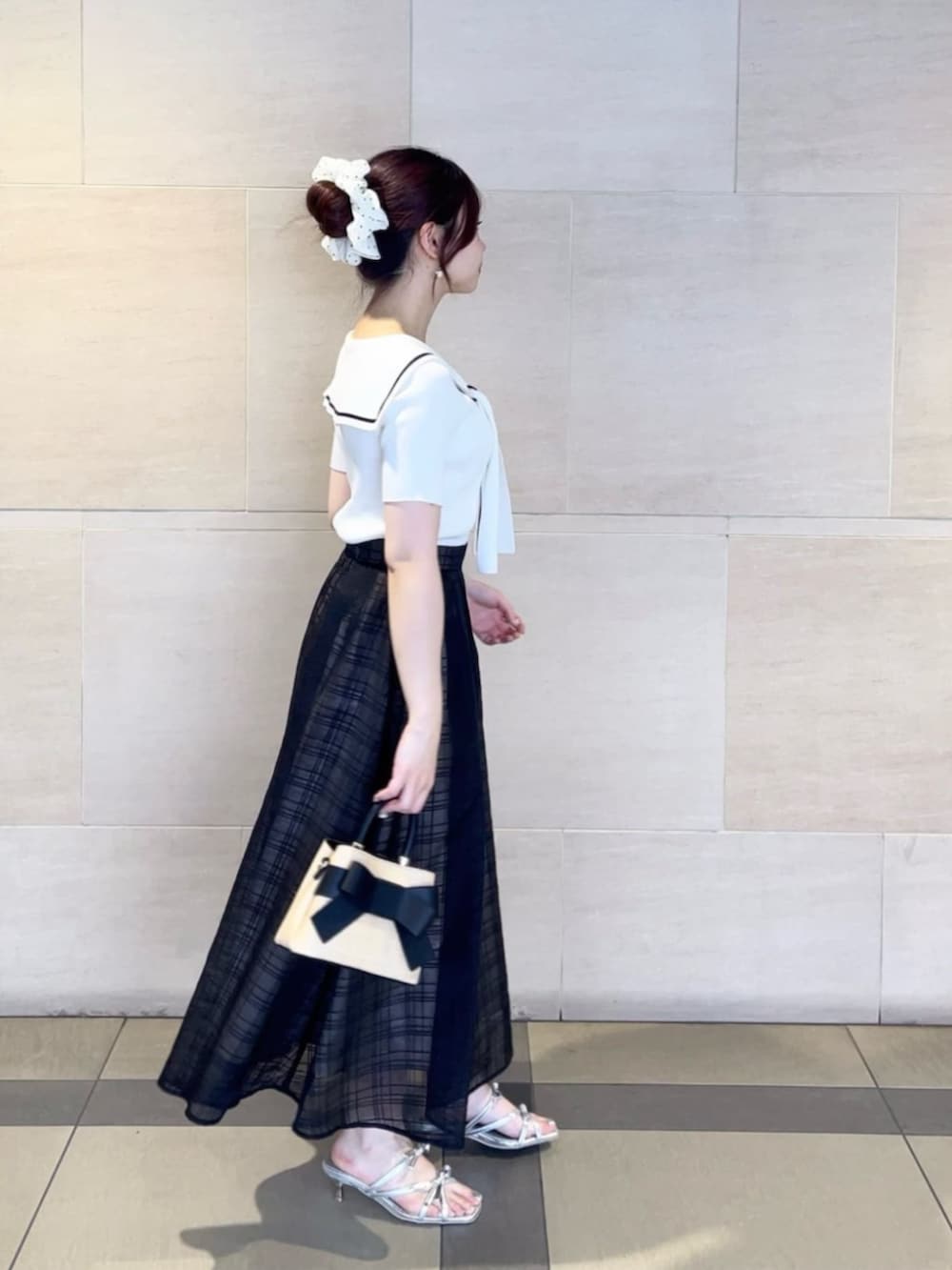 シルバー系のパンプス、ブラック系のショルダーバッグ、ホワイト系のニット/セーターを着用したレディースの夏コーディネートの2枚目の写真