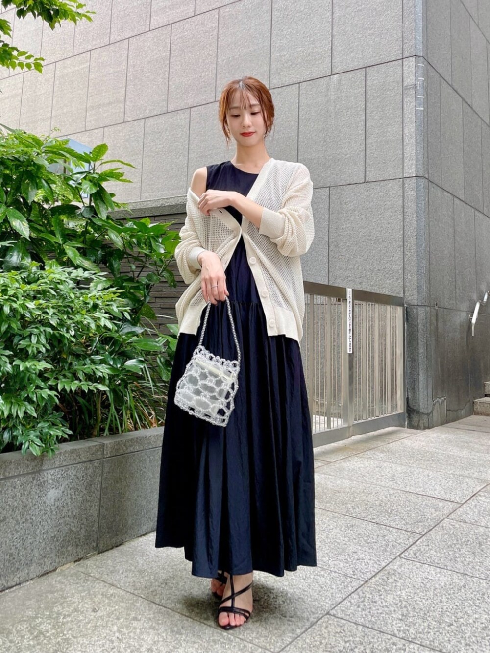 ブラック系のパンプス、ホワイト系のニット/セーター、ブラック系のワンピースを着用したレディースの夏コーディネートの2枚目の写真