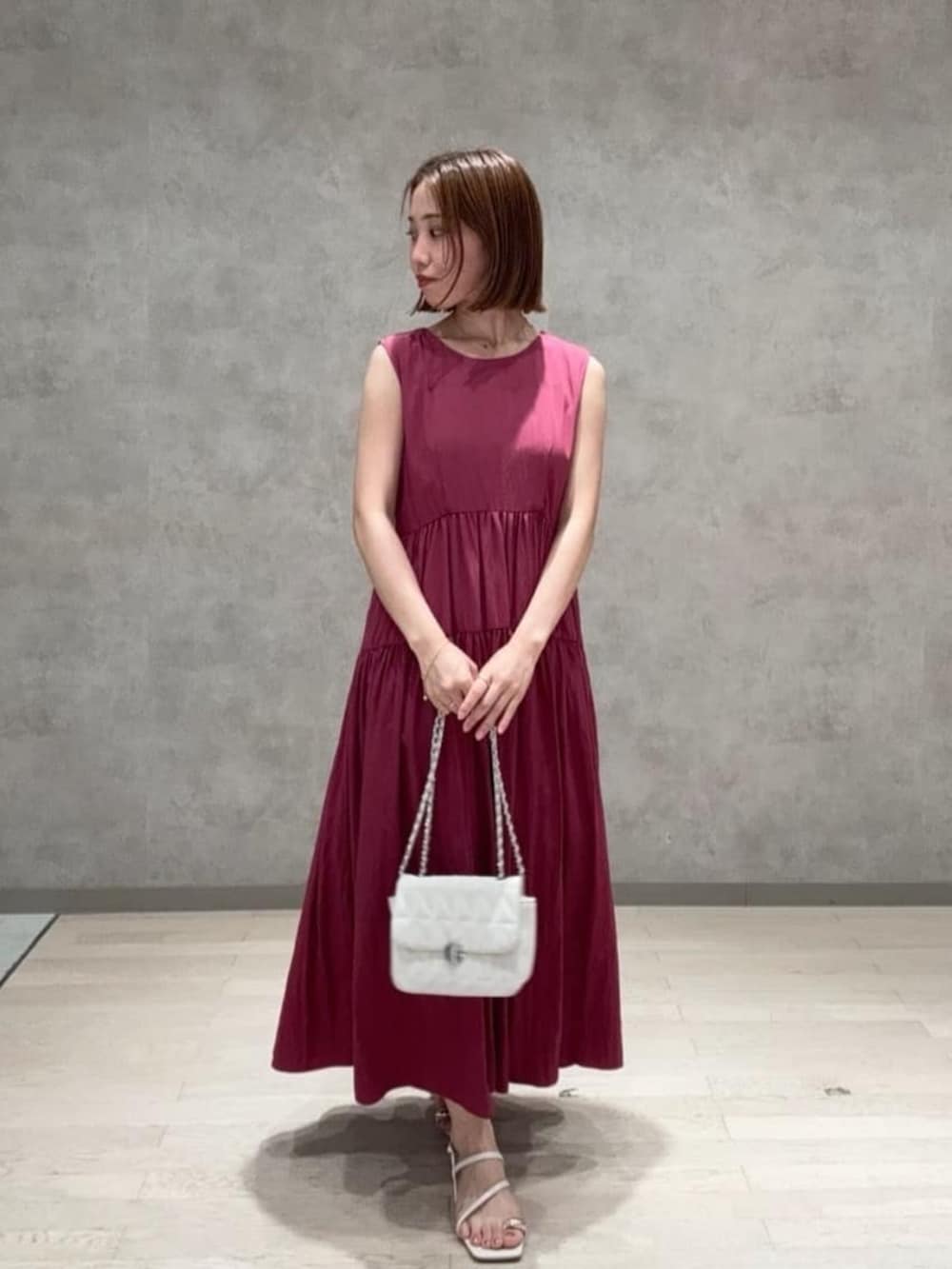 ホワイト系のショルダーバッグ、ピンク系のワンピース、ホワイト系のパンプスを着用したレディースの夏コーディネートの2枚目の写真