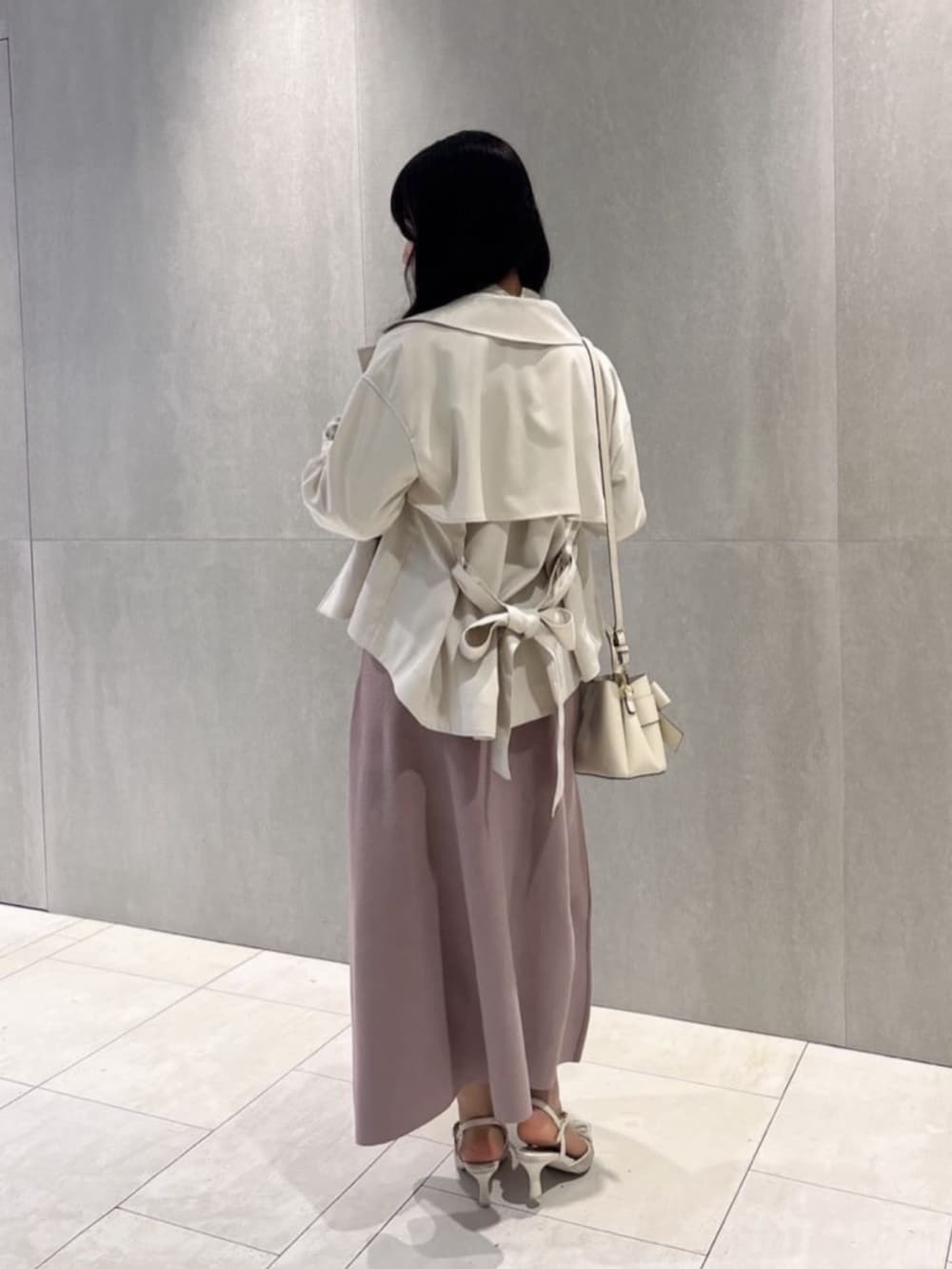 ホワイト系のショルダーバッグ、ベージュ系のトレンチコート、ピンク系のワンピースを着用したレディースの春コーディネートの3枚目の写真