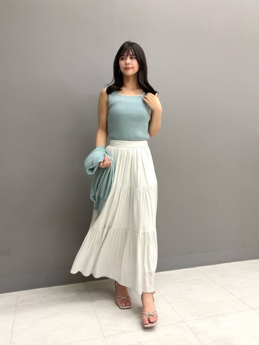 ホワイト系のショルダーバッグ、ホワイト系のスカート、グリーン系のパーカーを着用したレディースの夏コーディネートの2枚目の写真