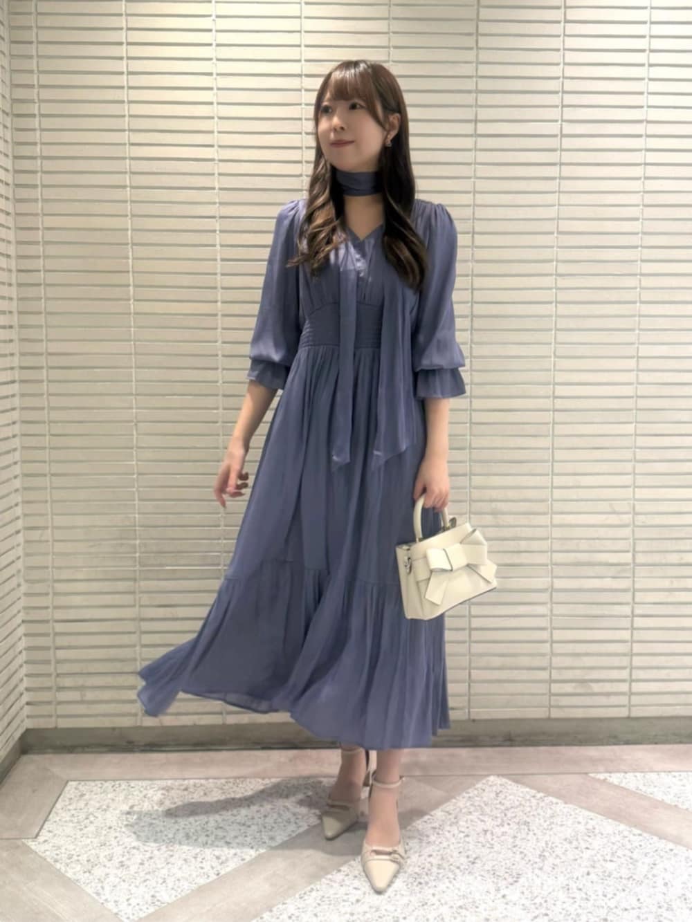 ホワイト系のショルダーバッグ、ベージュ系のパンプス、ブルー系のワンピースを着用したレディースの春コーディネートの2枚目の写真