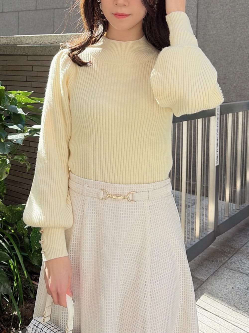 ホワイト系のショルダーバッグ、イエロー系のニット/セーター、ホワイト系のスカートを着用したレディースの冬コーディネートの3枚目の写真