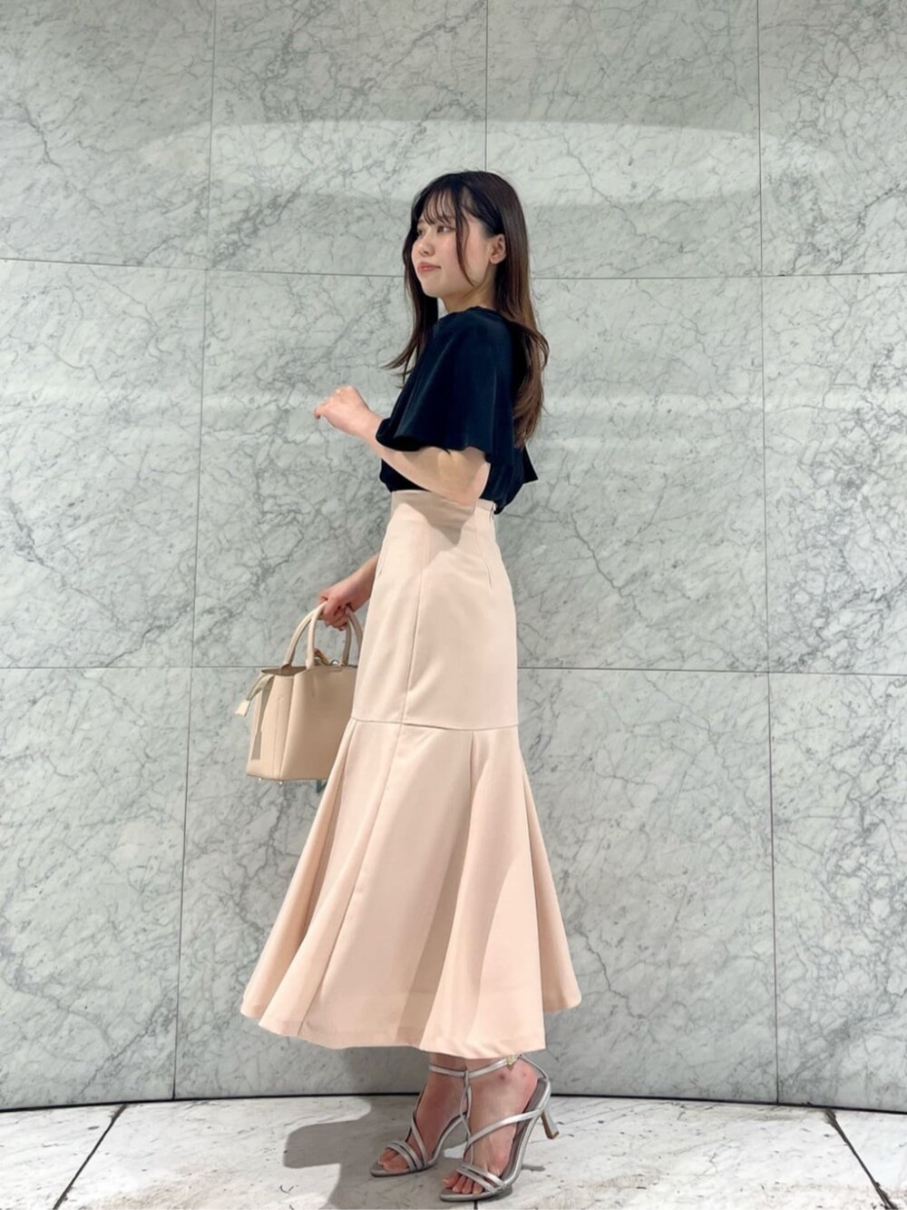 シルバー系のパンプス、ブラック系のシャツ/ブラウス、ピンク系のスカートを着用したレディースの春コーディネートの2枚目の写真