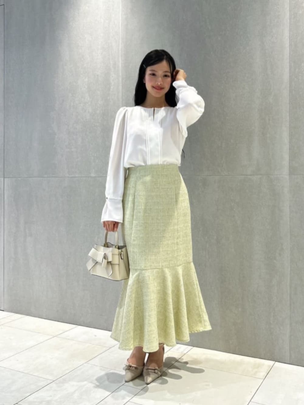 ホワイト系のショルダーバッグ、ベージュ系のパンプス、ホワイト系のシャツ/ブラウスを着用したレディースの冬コーディネートの2枚目の写真