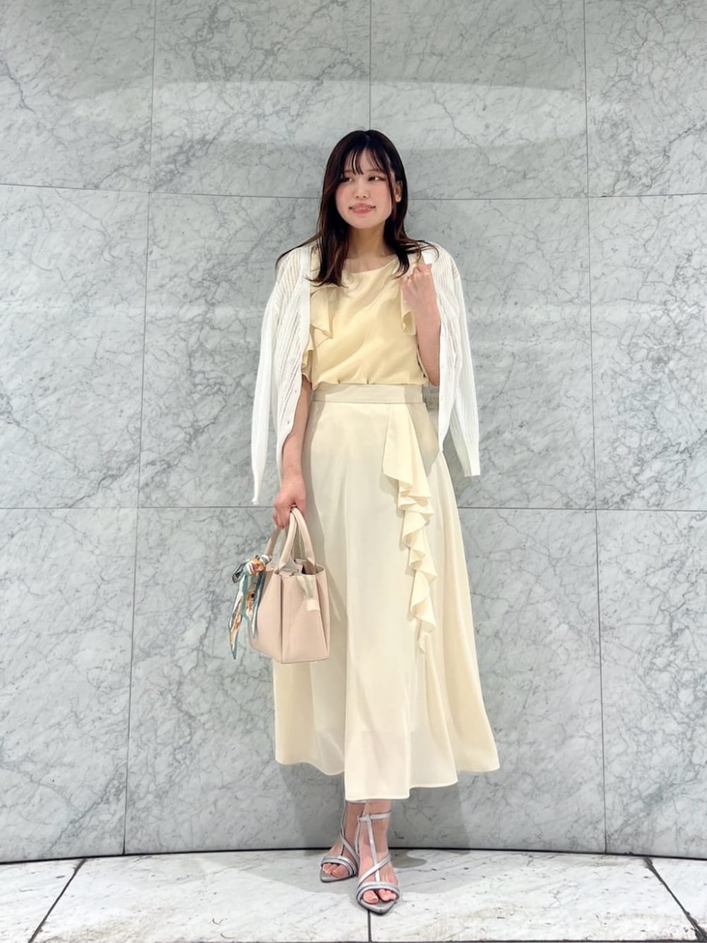 シルバー系のパンプス、ホワイト系のカーディガン/ボレロ、ベージュ系のトートバッグを着用したレディースの春コーディネートの3枚目の写真