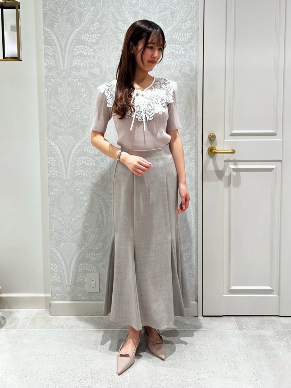 ブラウン系のスカート、ピンク系のニット/セーター、ピンク系のパンプスを着用したレディースの夏コーディネートの2枚目の写真