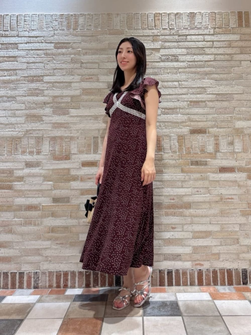 シルバー系のパンプス、ブラック系のショルダーバッグ、ブラウン系のワンピースを着用したレディースの夏コーディネートの2枚目の写真