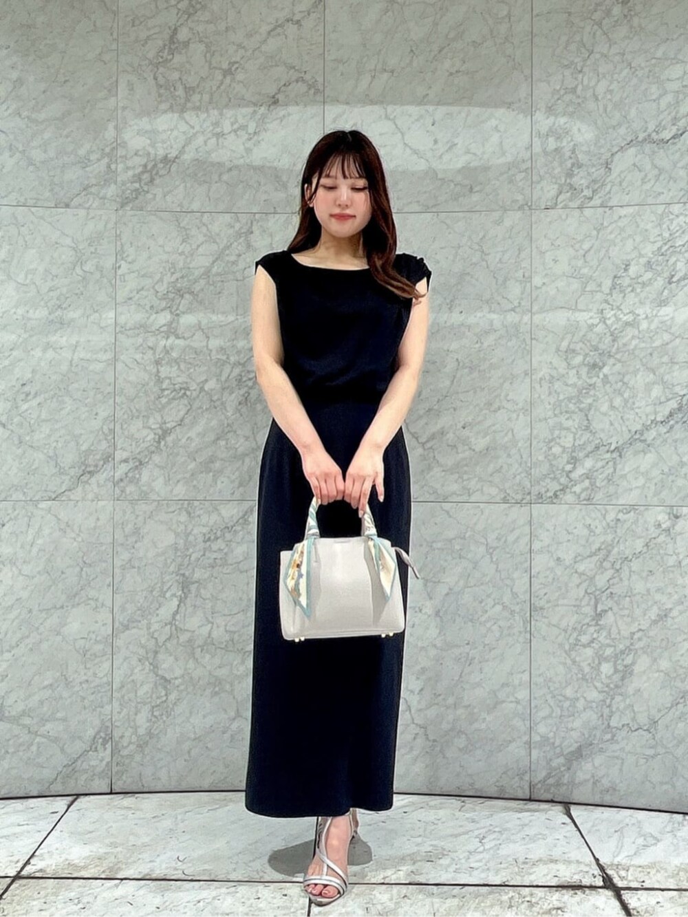 シルバー系のパンプス、ブラック系のワンピース、グレー系のトートバッグを着用したレディースの夏コーディネートの2枚目の写真