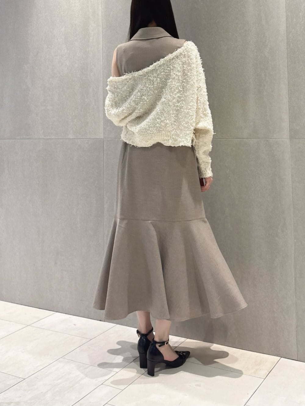 ブラック系のパンプス、ホワイト系のカーディガン/ボレロ、ベージュ系のワンピースを着用したレディースの春コーディネートの3枚目の写真