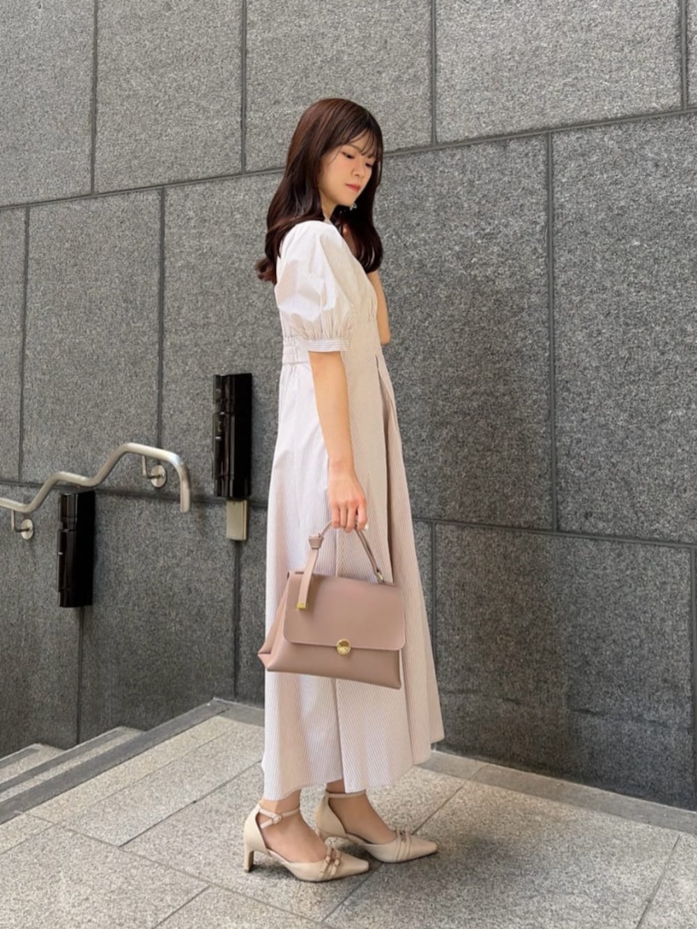 ベージュ系のパンプス、ベージュ系のワンピース、ブラウン系のトートバッグを着用したレディースの春コーディネートの3枚目の写真