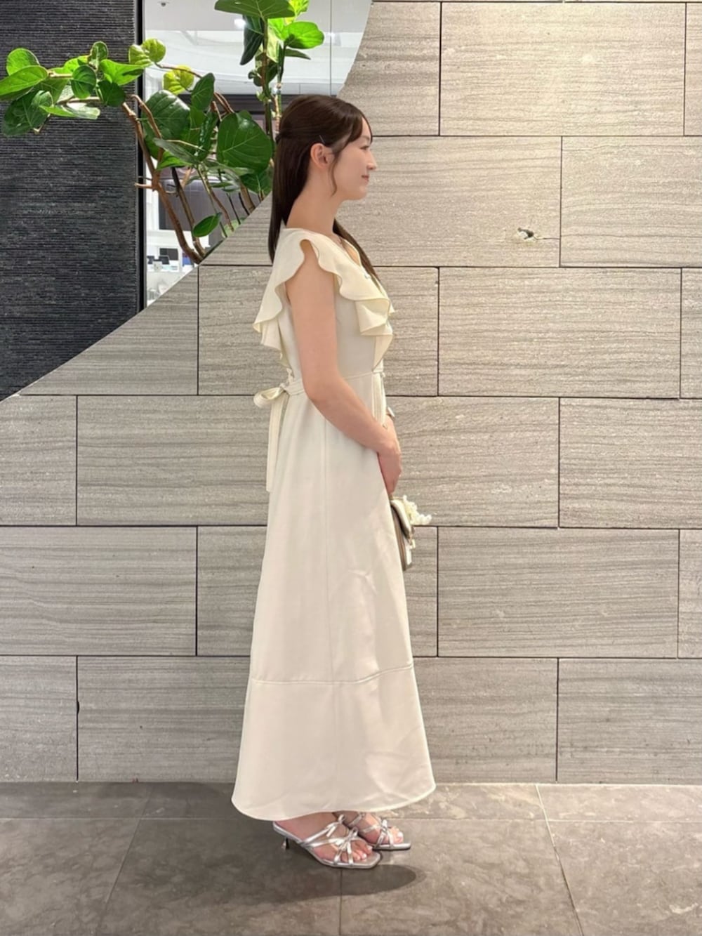 シルバー系のパンプス、グレー系のショルダーバッグ、ベージュ系のワンピースを着用したレディースの夏コーディネートの2枚目の写真