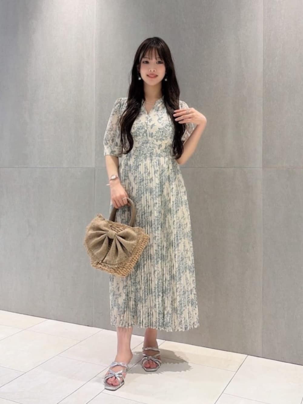 シルバー系のパンプス、ホワイト系のワンピース、ベージュ系のショルダーバッグを着用したレディースの夏コーディネートの2枚目の写真