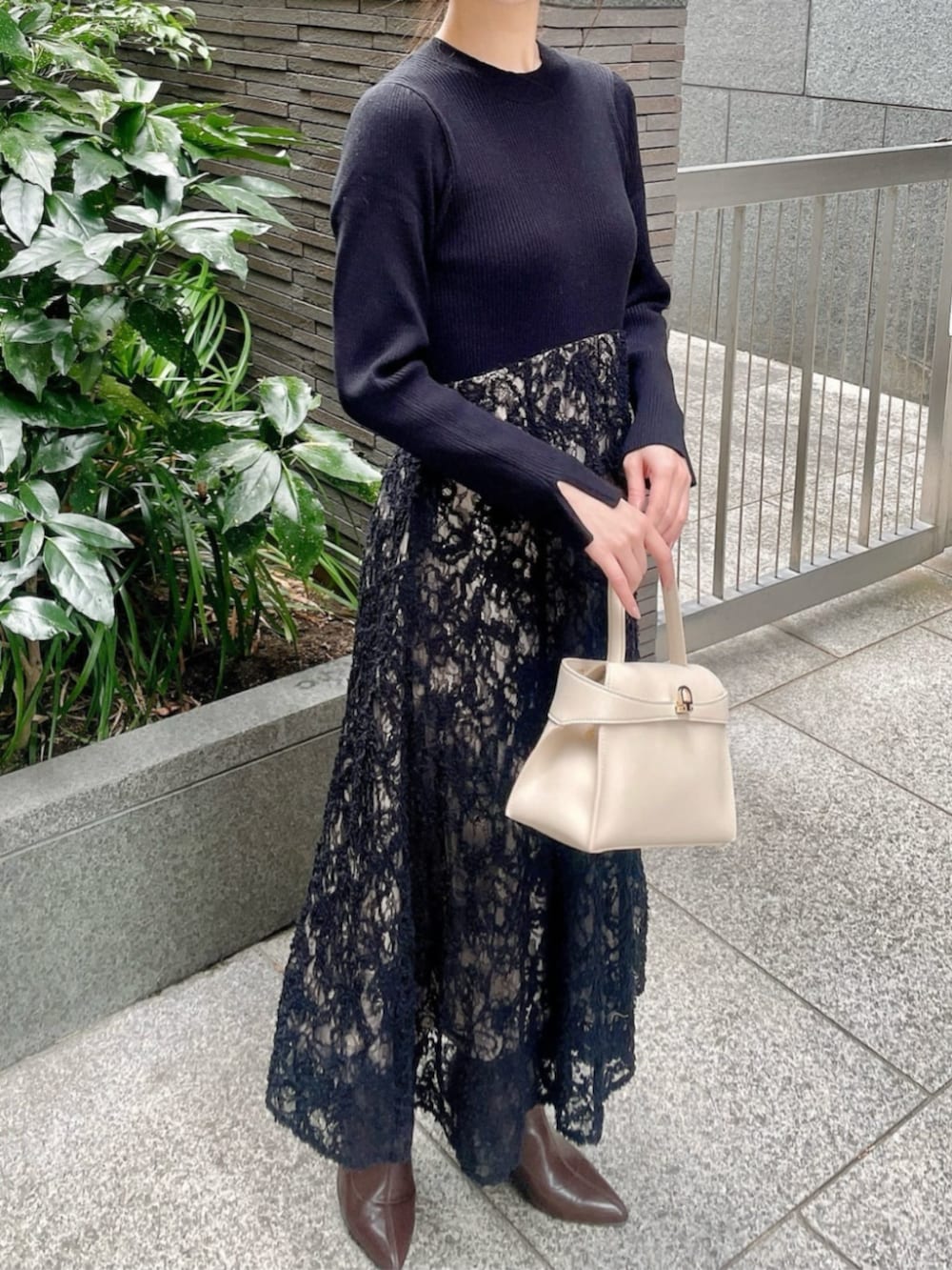 ホワイト系のトートバッグ、ブラック系のワンピースを着用したレディースの冬コーディネートの3枚目の写真